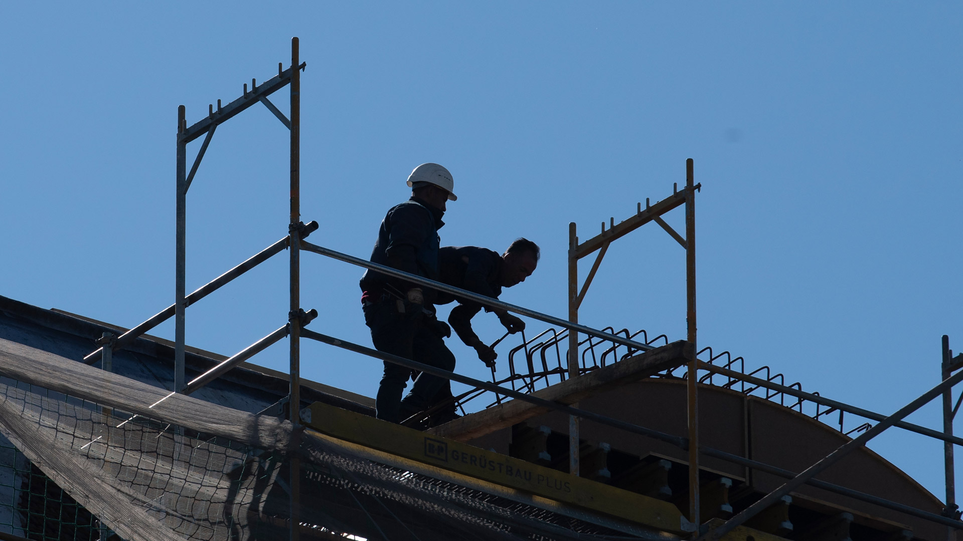 Silhouette zweier Arbeiter auf einer Baustelle.