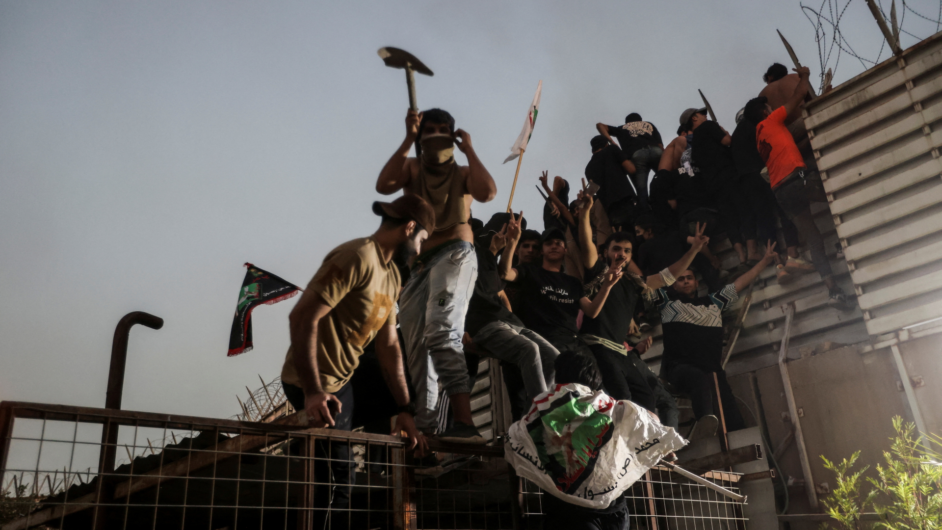 Demonstranten klettern über eine Absperrung an der schwedischen Botschaft in Bagdad.