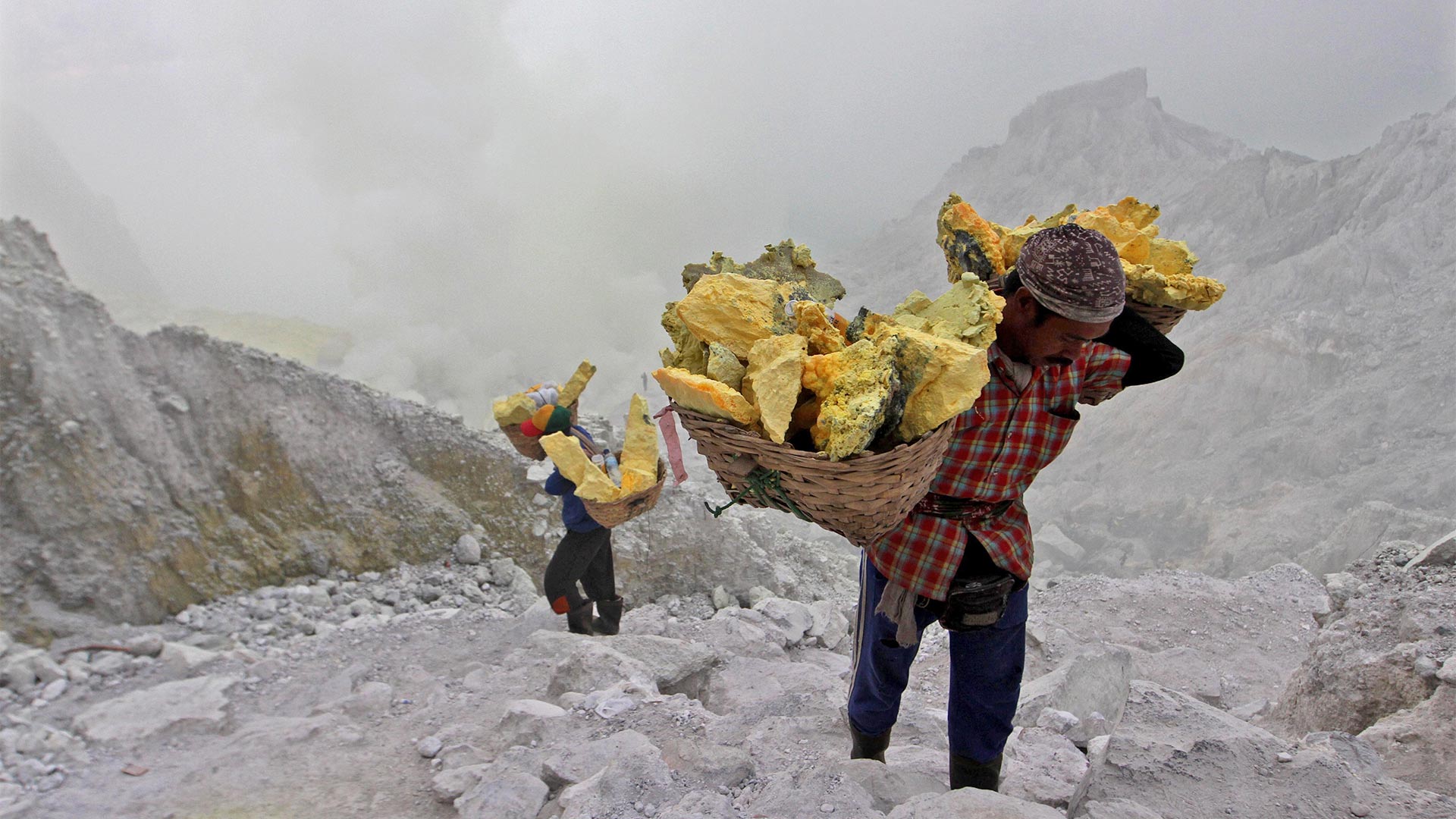 Arbeiter schleppen Schwefel aus einem Vulkankrater in Indonesien.