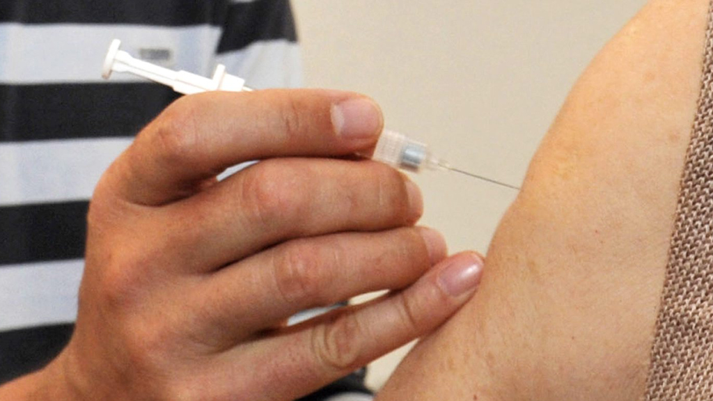 Ein Arzt spritzt einem Patienten ein Mittel gegen Grippe (Archivbild)
