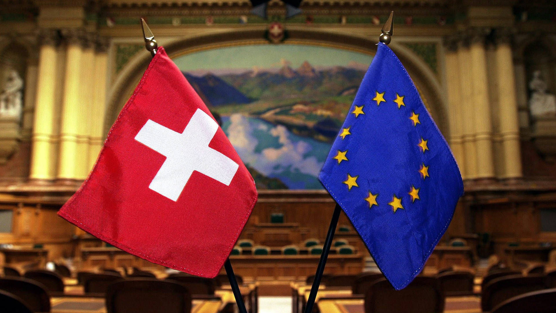 Flaggen der Schweiz und der EU stehen im Nationalratssaal in Bern.