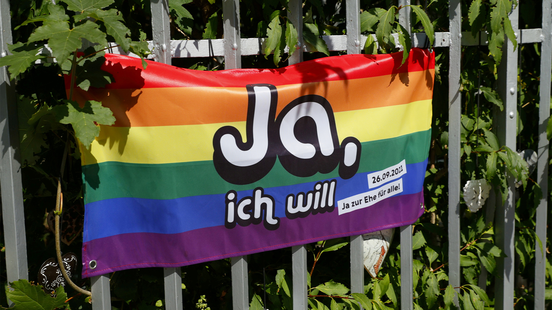An einem Zaun hängt ein Banner in Regenbogenfarben mit dem Aufdruck "Ja, ich will". | REUTERS