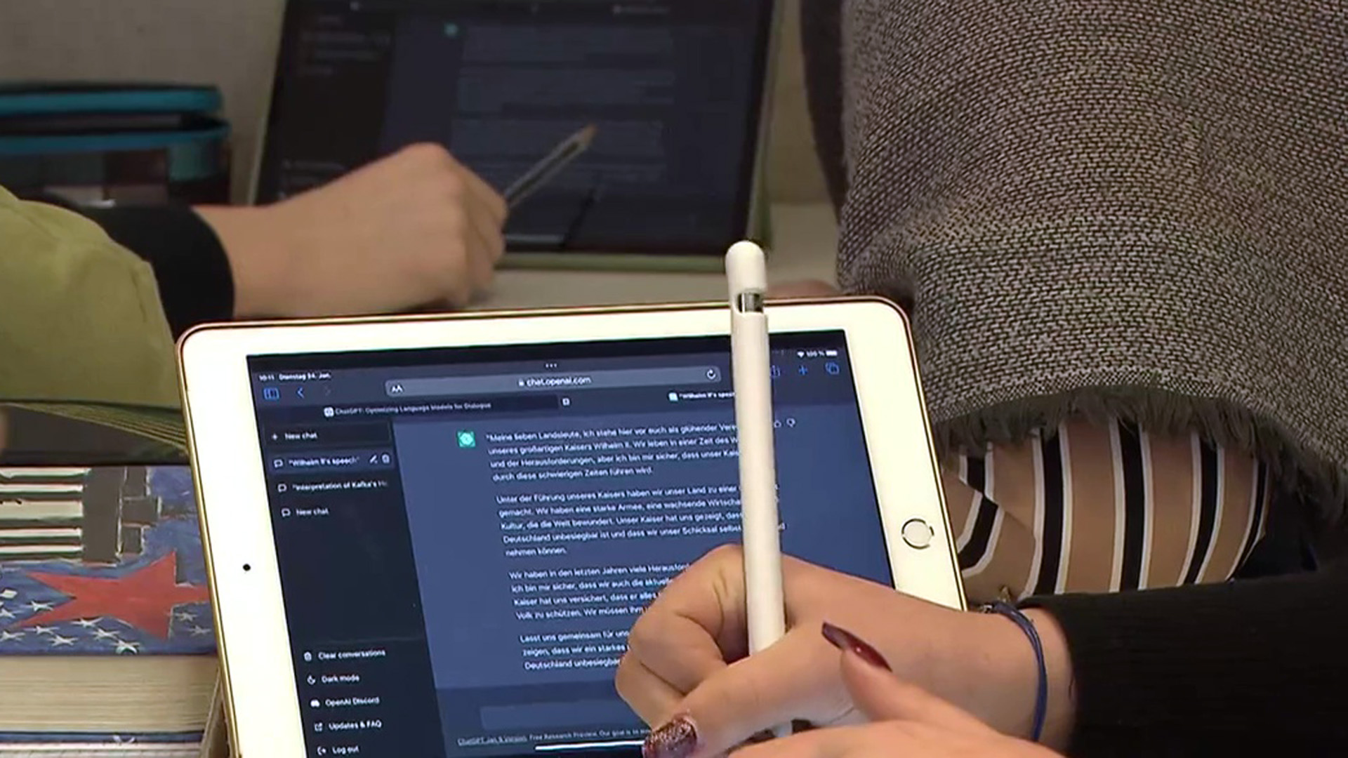 Eine Hand vor einem Tablet, auf dem ein Text zu sehen ist.