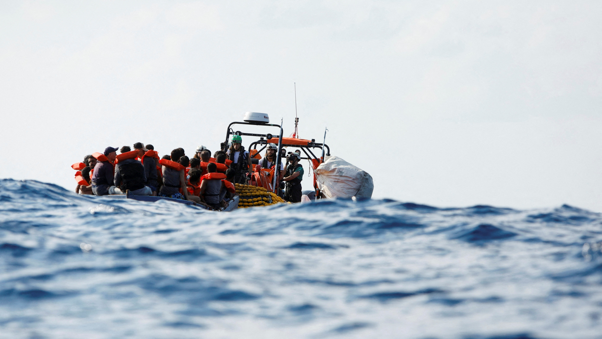 Besatzungsmitglieder des Flüchtlingsrettungsschiffs "Geo Barents", das von Ärzte ohne Grenzen betrieben wird, verteilen während einer Rettungsaktion in internationalen Gewässern vor der Küste Libyens Schwimmwesten an eine Gruppe von 61 Migranten auf einem Holzboot (aufgenommen am 28. September 2023)