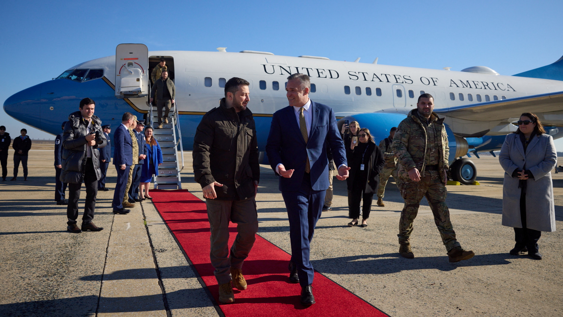 Wolodymyr Selenskyj und Rufus Gifford laufen nach dem Aussteigen aus einem US-Regierungsflugzeug über einen roten Teppich.  | via REUTERS