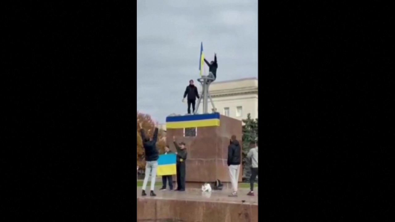 Ein Mann schwenkt eine ukrainische Flagge auf einer Statue in Cherson (Screenshot) | Reuters
