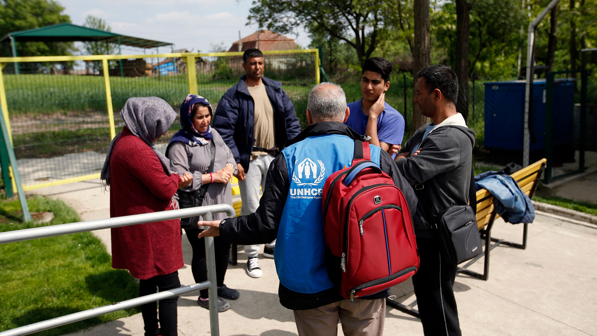Ein UNHCR-Mitarbeiter spricht vor einer Flüchtlingsunterkunft mit afghanischen Asylbewerber, die aus Ungarn nach Serbien abgeschoben wurden | dpa