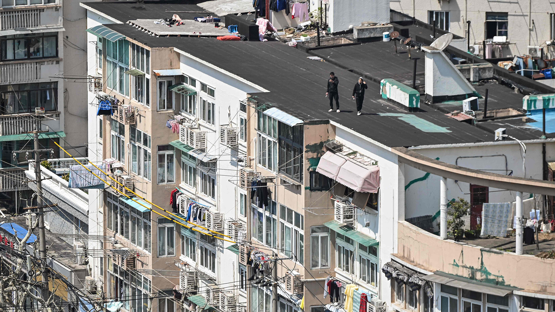 Auf dem Dach eines Häuserblocks stehen zwei Menschen. | AFP