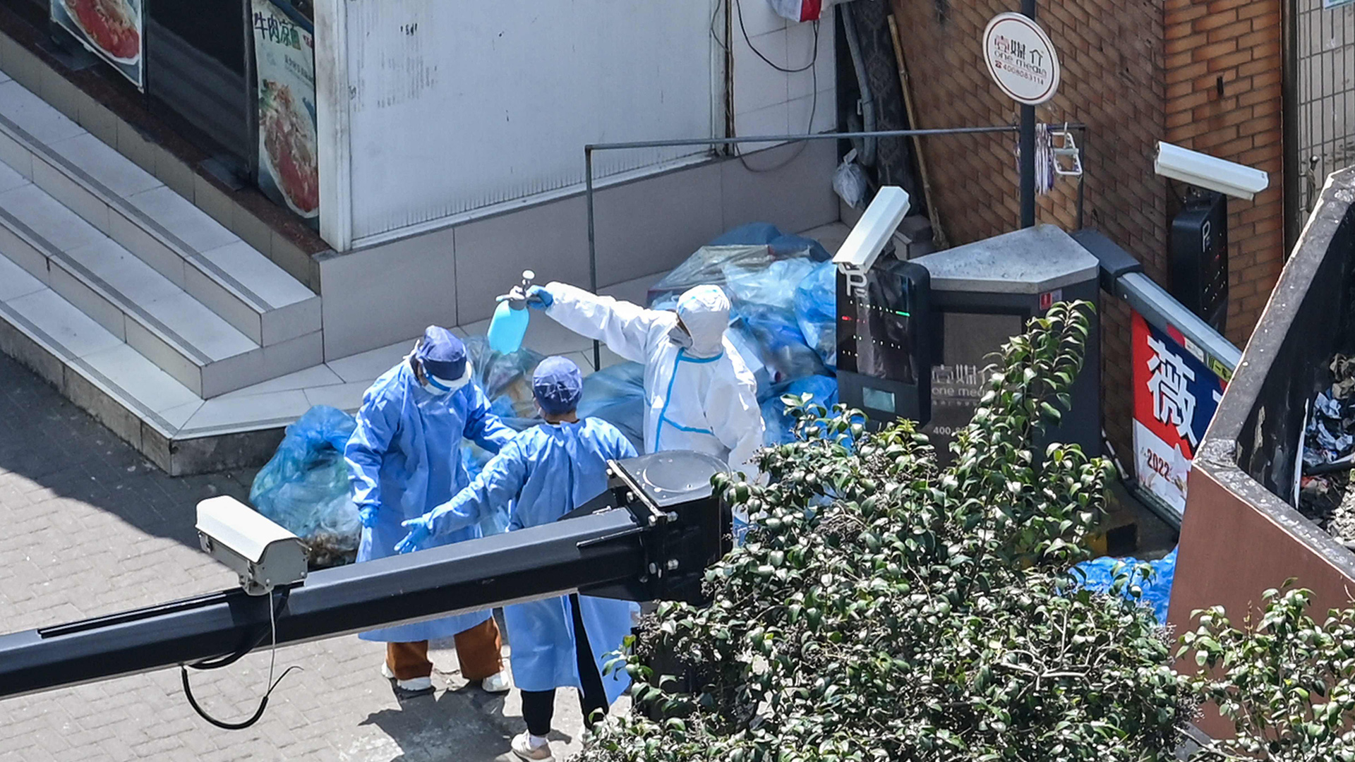 Ein Arbeiter in Schutzkleidung sprüht Desinfektionsmittel über seine Kollegen. | AFP