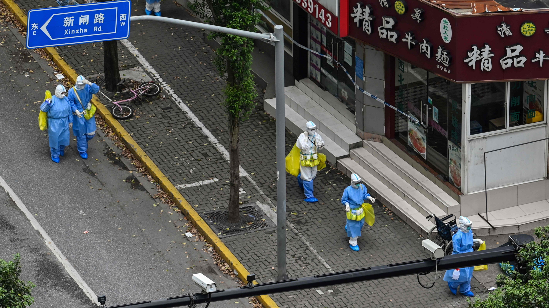 Mitarbeiter der Gesundheitsdienste in Schutzanzügen auf einer Straße in Shanghai