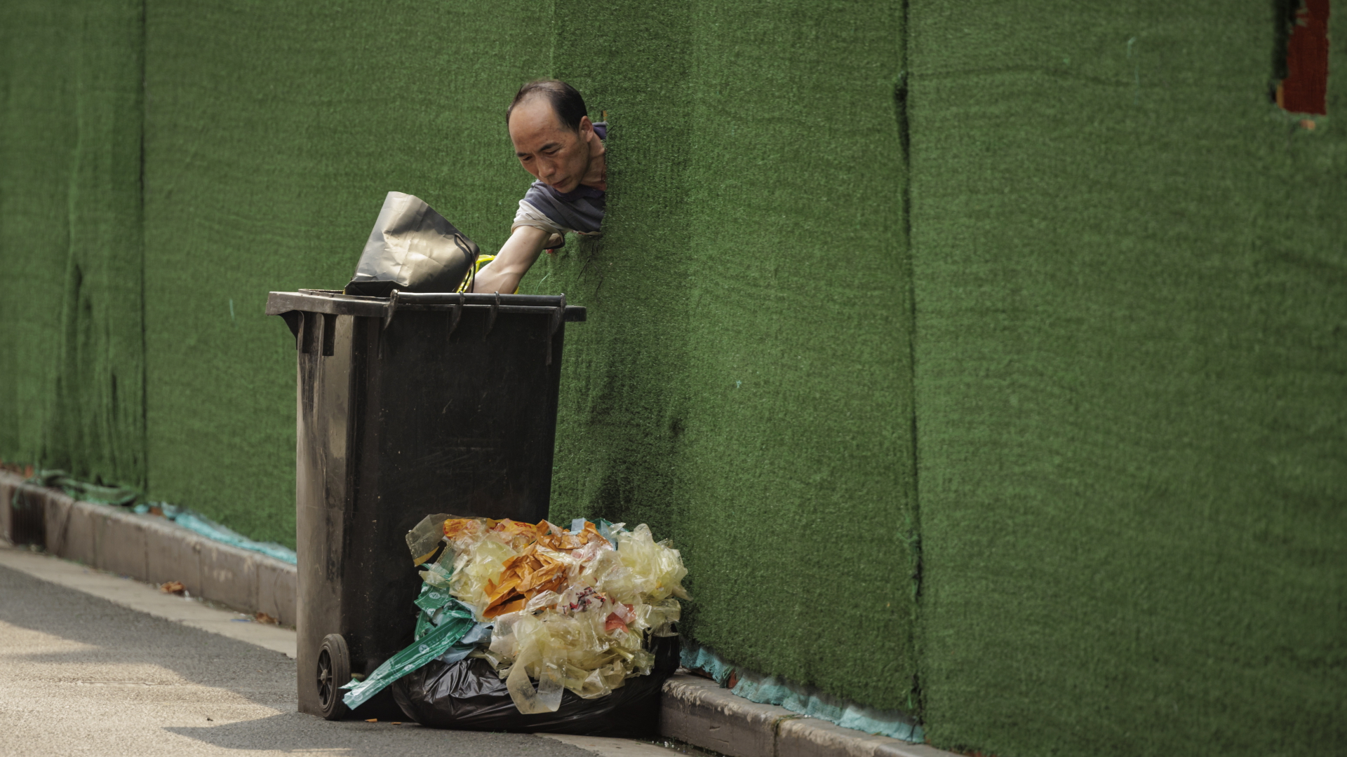Ein Mann steckt in Shanghai seinen Kopf durch eine Absperrung. | EPA