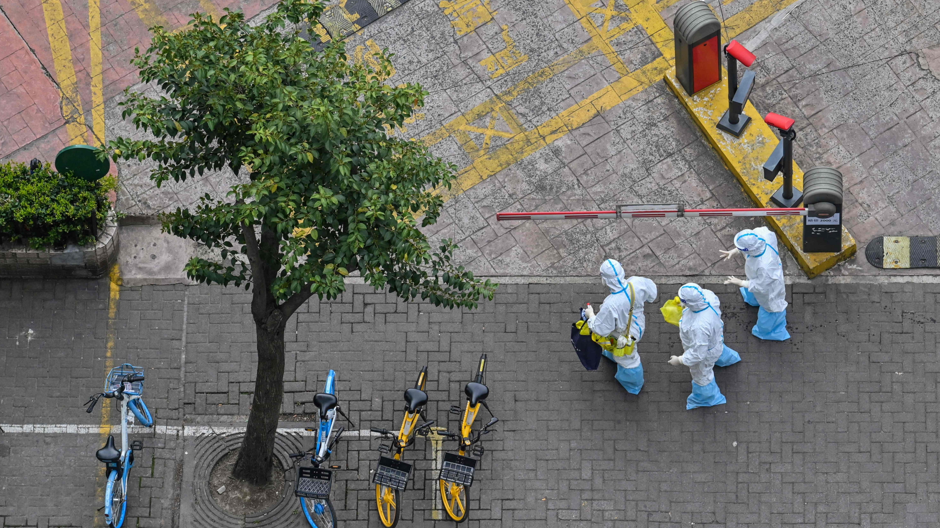 Freiwillige in Schutzausrüstung gehen durch eine leere Straße in Shanghai. | AFP