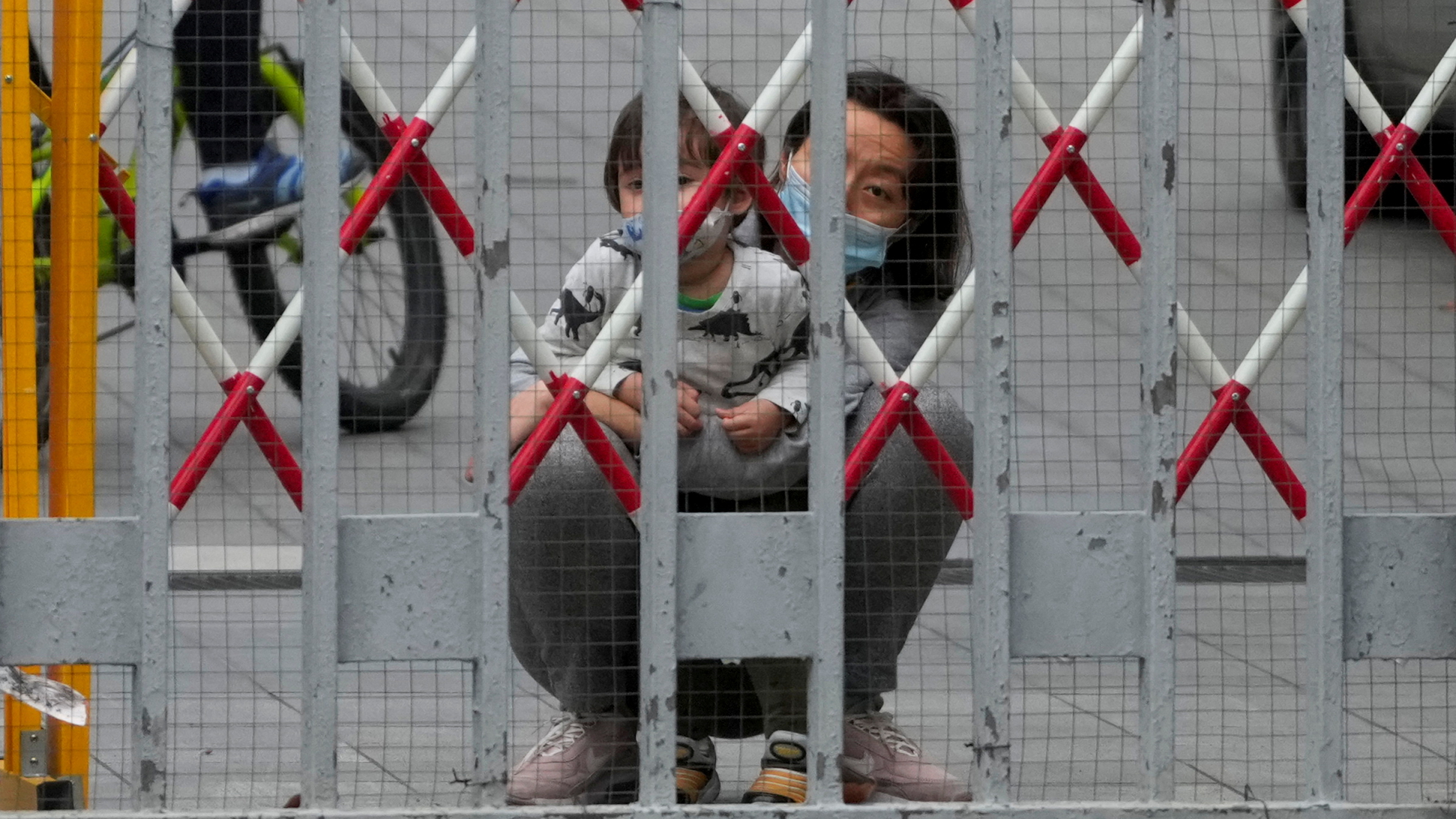 Eine Frau und ein Kind hocken hinter einer Absperrung in Shanghai. | REUTERS