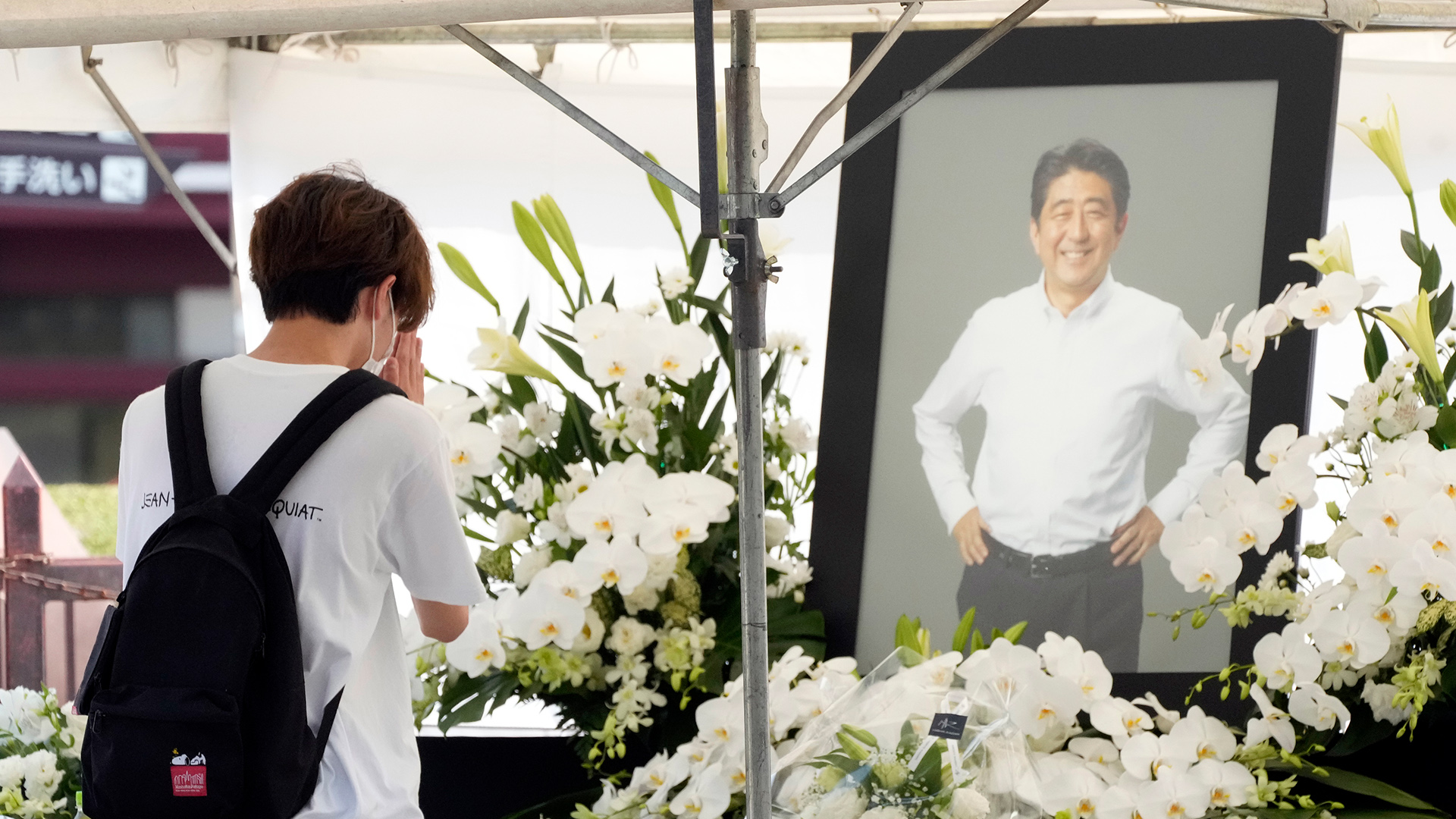 Eine Person legt Blumen am Zojoji-Tempel nieder und betet vor einem Foto von Japans ehemaligen Premierministers Shinzo Abe. | dpa