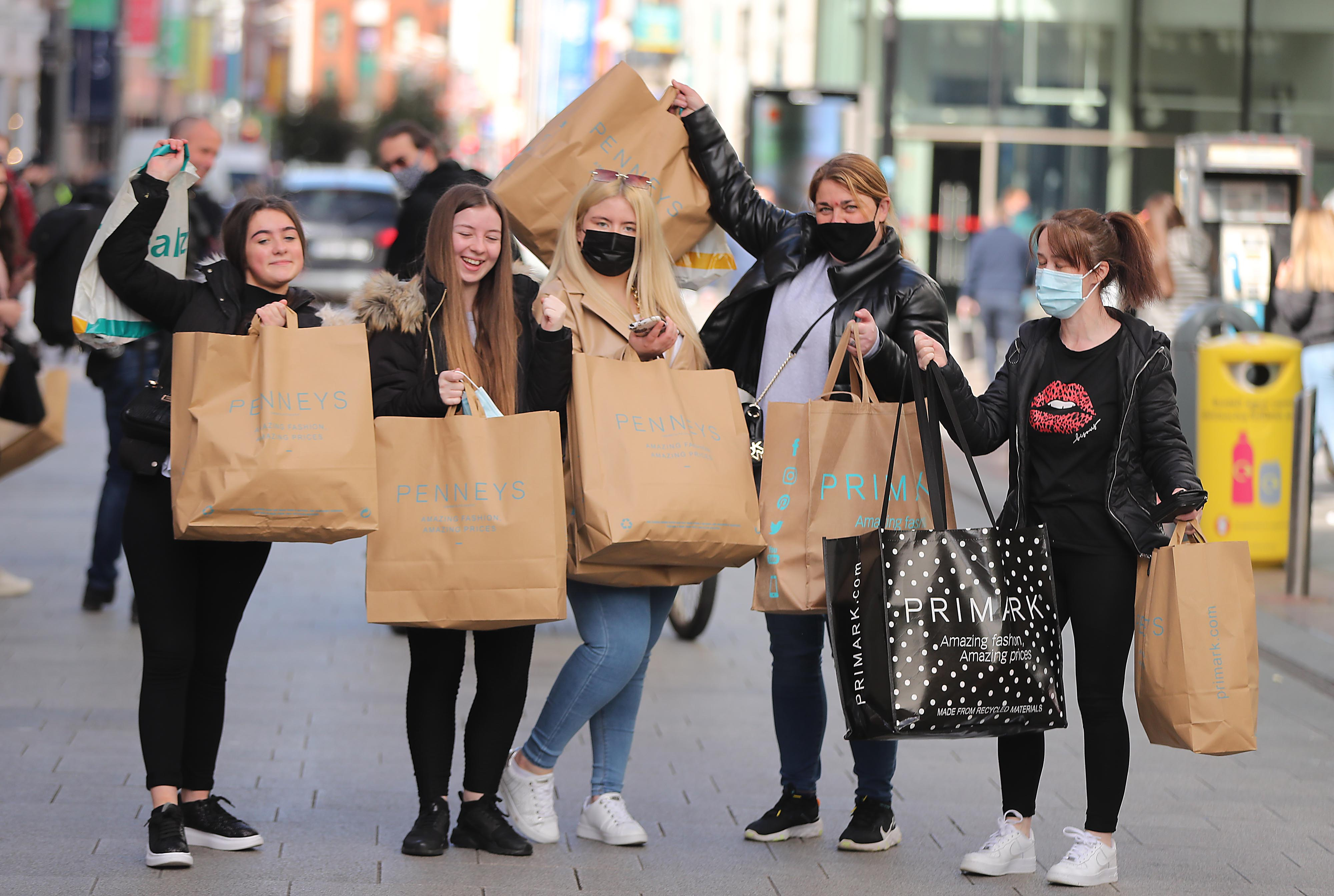 Junge Frauen heben ihre Einkaufstüten nach einer Shopping-Tour in die Höhe | picture alliance/dpa/PA Wire