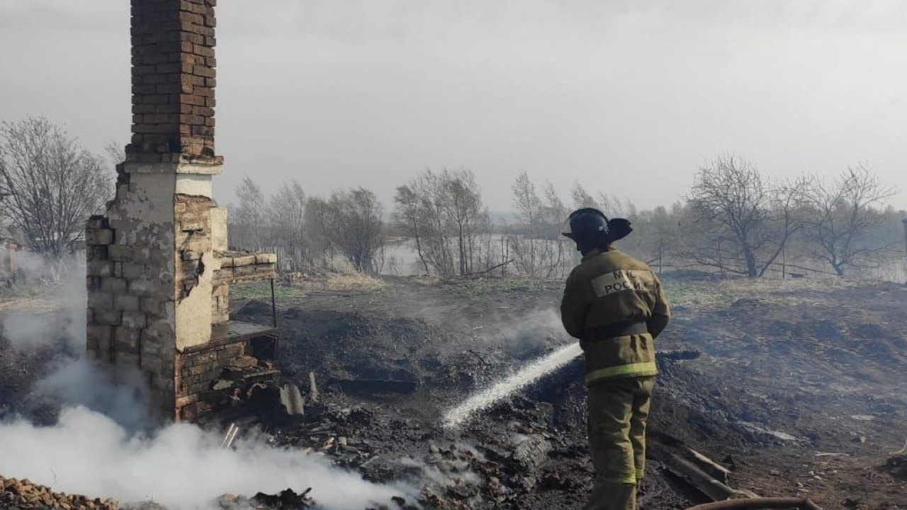 Ein Feuerwehrmann löscht die glühenden Überreste eines Wohnhauses in Sibirien. | AFP