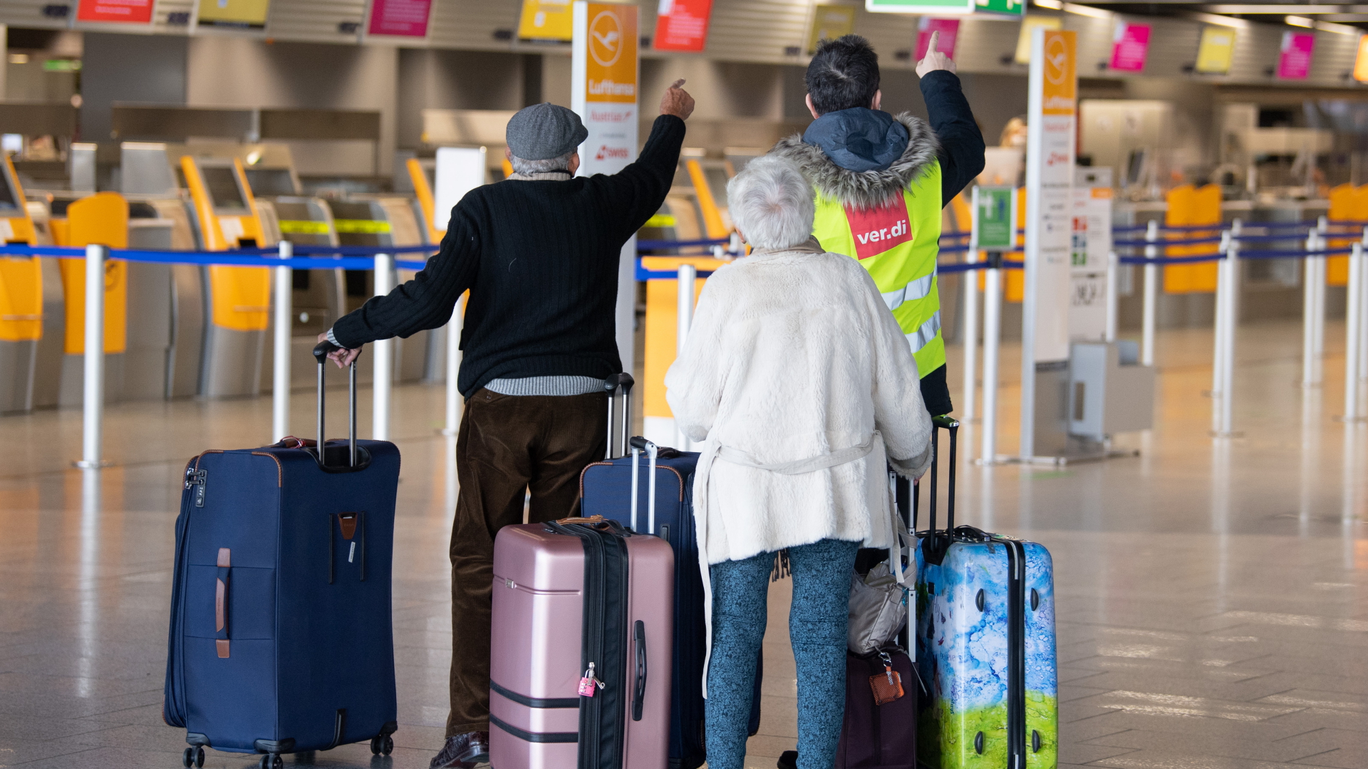 Ein Mann mit einer Weste mit Verdi-Schriftzug spricht im Terminal 1 des Flughafens Frankfurt mit Reisenden.  | dpa
