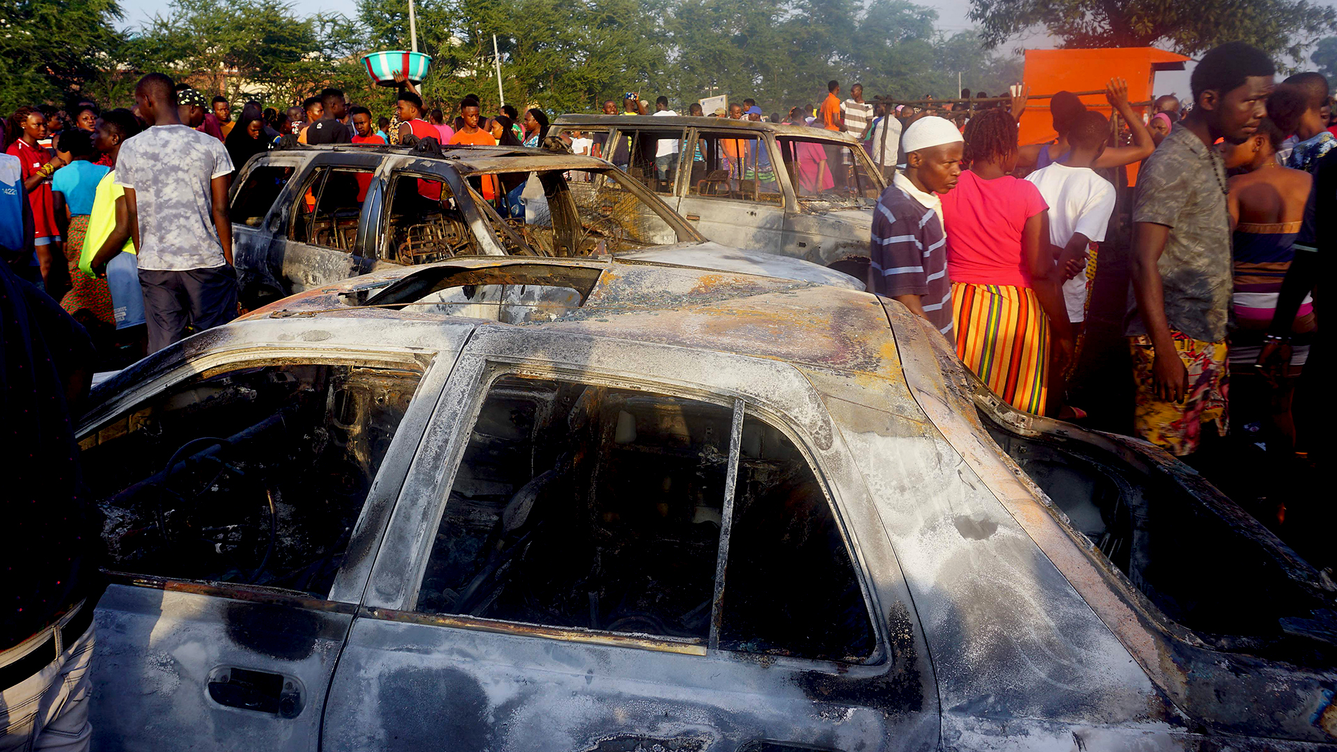 Menschen stehen am Unglücksort neben verbrannten Autos. | AFP