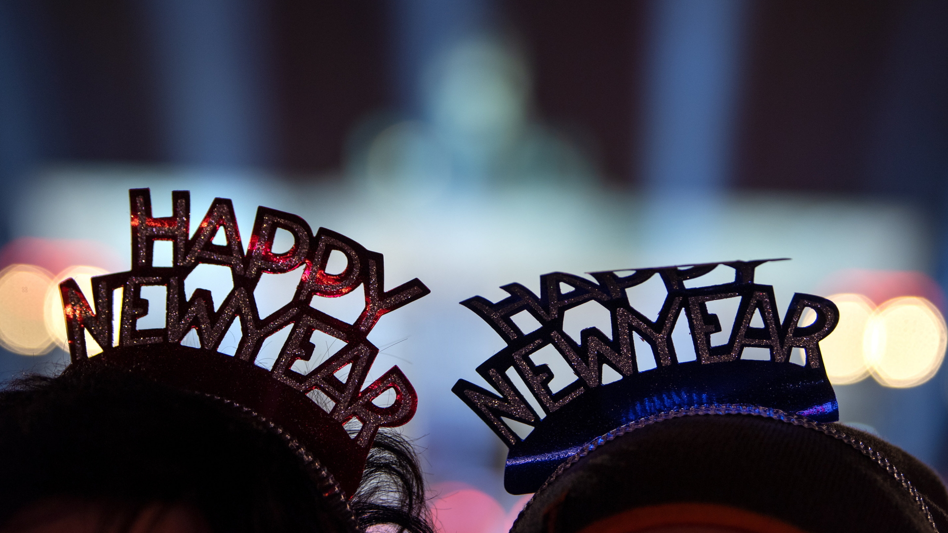 Zwei Männer tragen Kopfschmuck mit der Aufschrift "Happy New Year" auf Deutschlands größter Silvesterparty am Brandenburger Tor. | Bildquelle: dpa