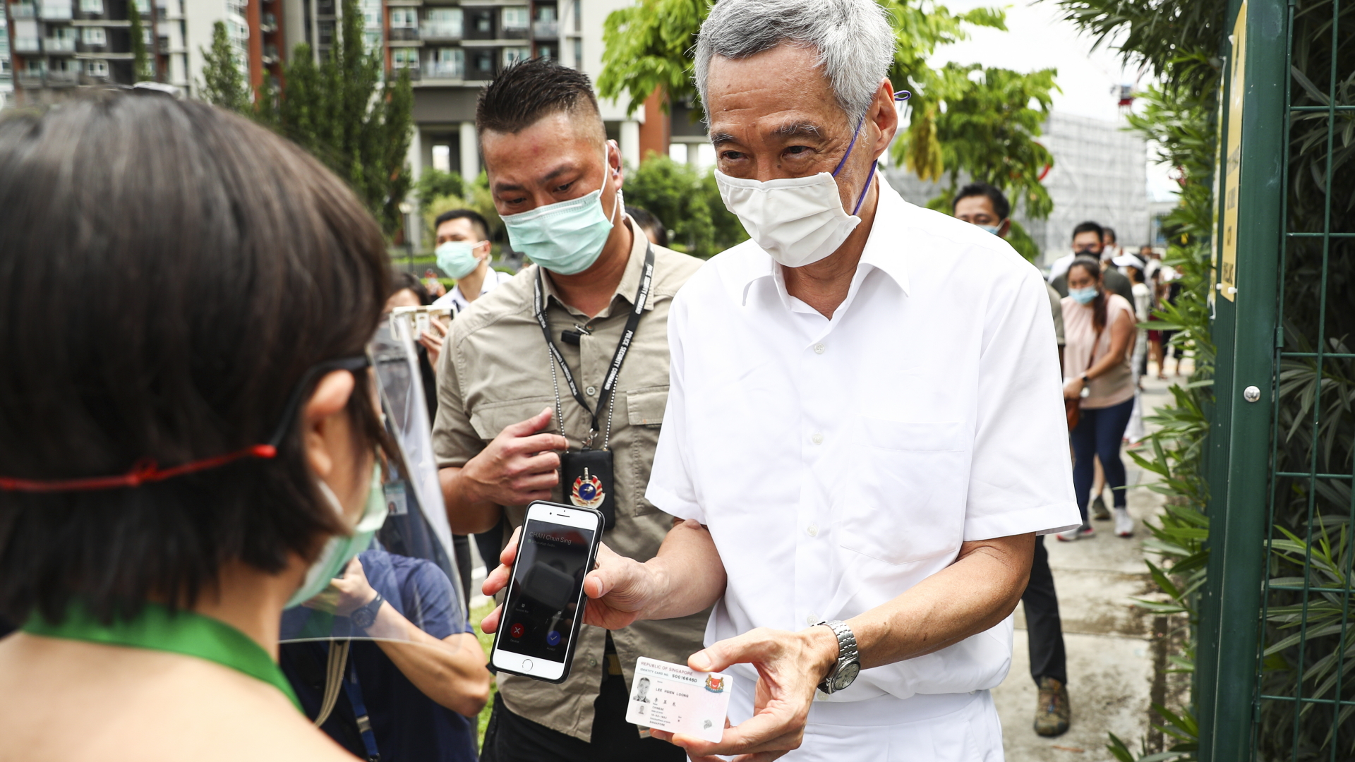 Lee Hsien Loong (M) verifiziert seine Identität vor einem Wahllokal für die Parlamentswahl.  | dpa