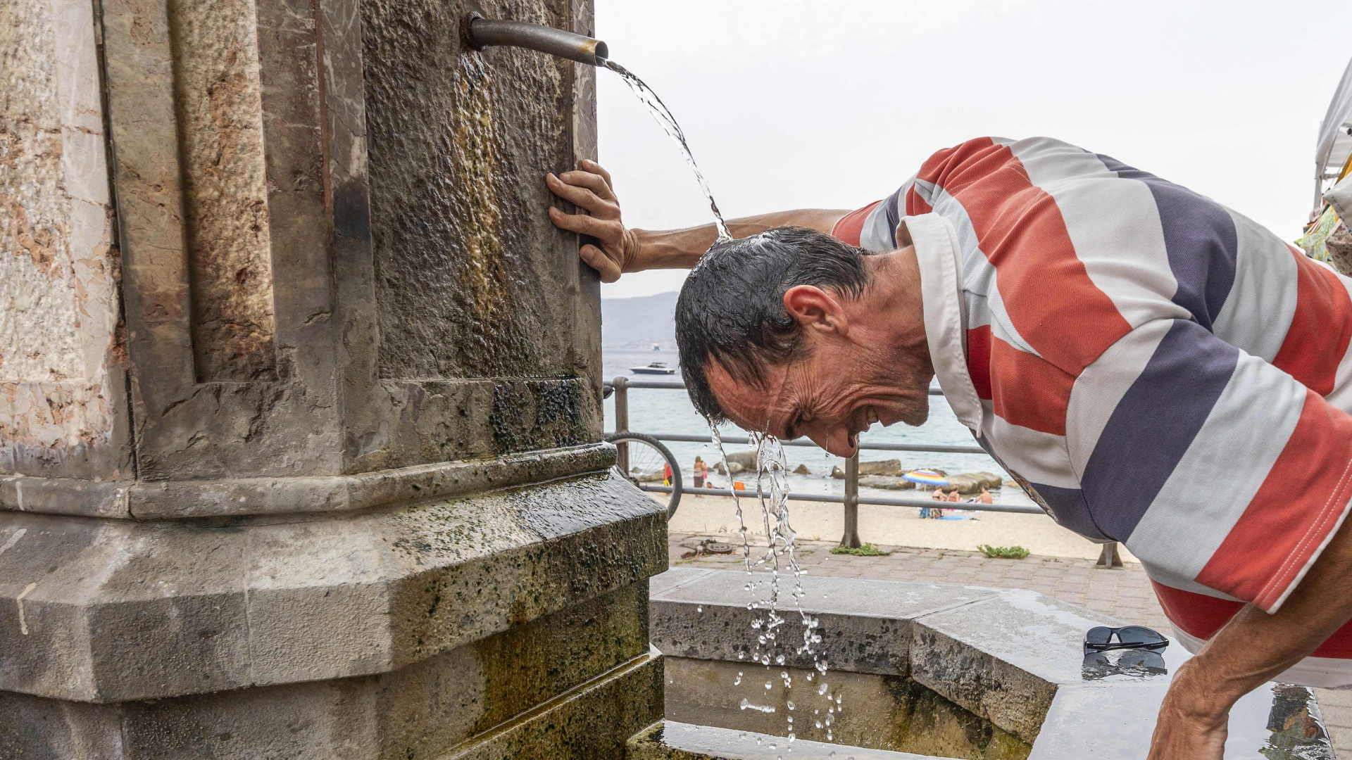 Ein Mann erfrischt sich an einem heißen Sommertag in Messina auf Sizilien. | AFP