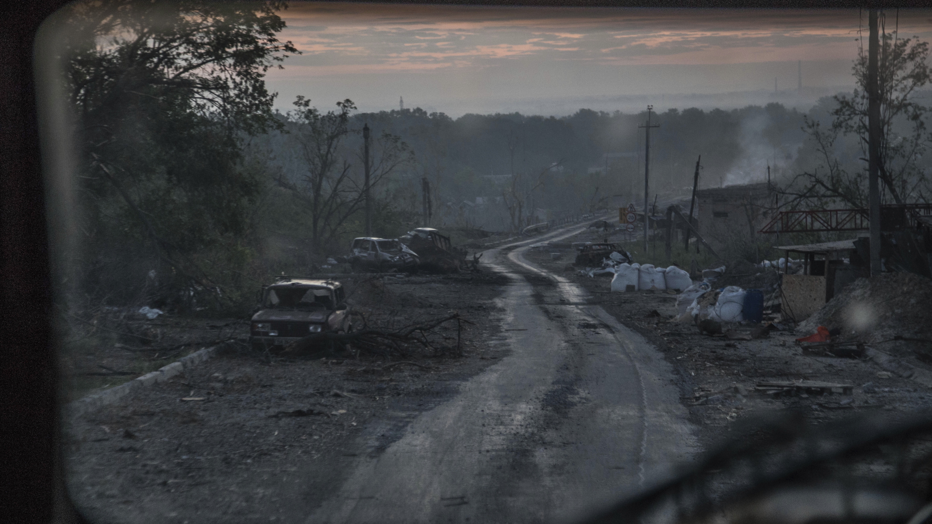 Während schwerer Kämpfe an der Front in Sjewjerodonezk in der Region Luhansk liegen ausgebrannte Autowracks am Rand eines Wegs. | dpa