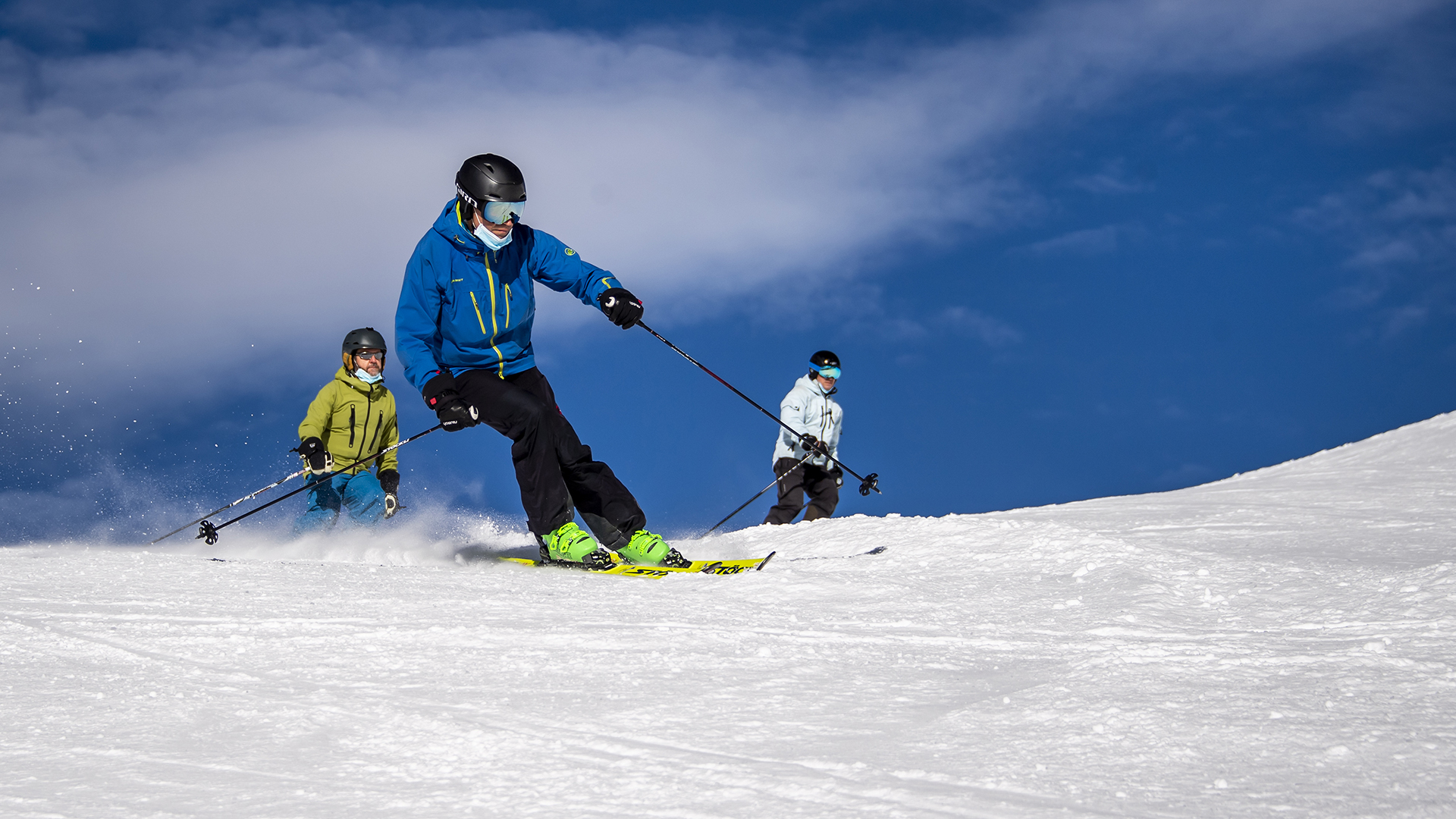 Skifahrer mit Mund-Nasen-Schutz fahren eine Piste im Walliser Skigebiet hinunter | dpa