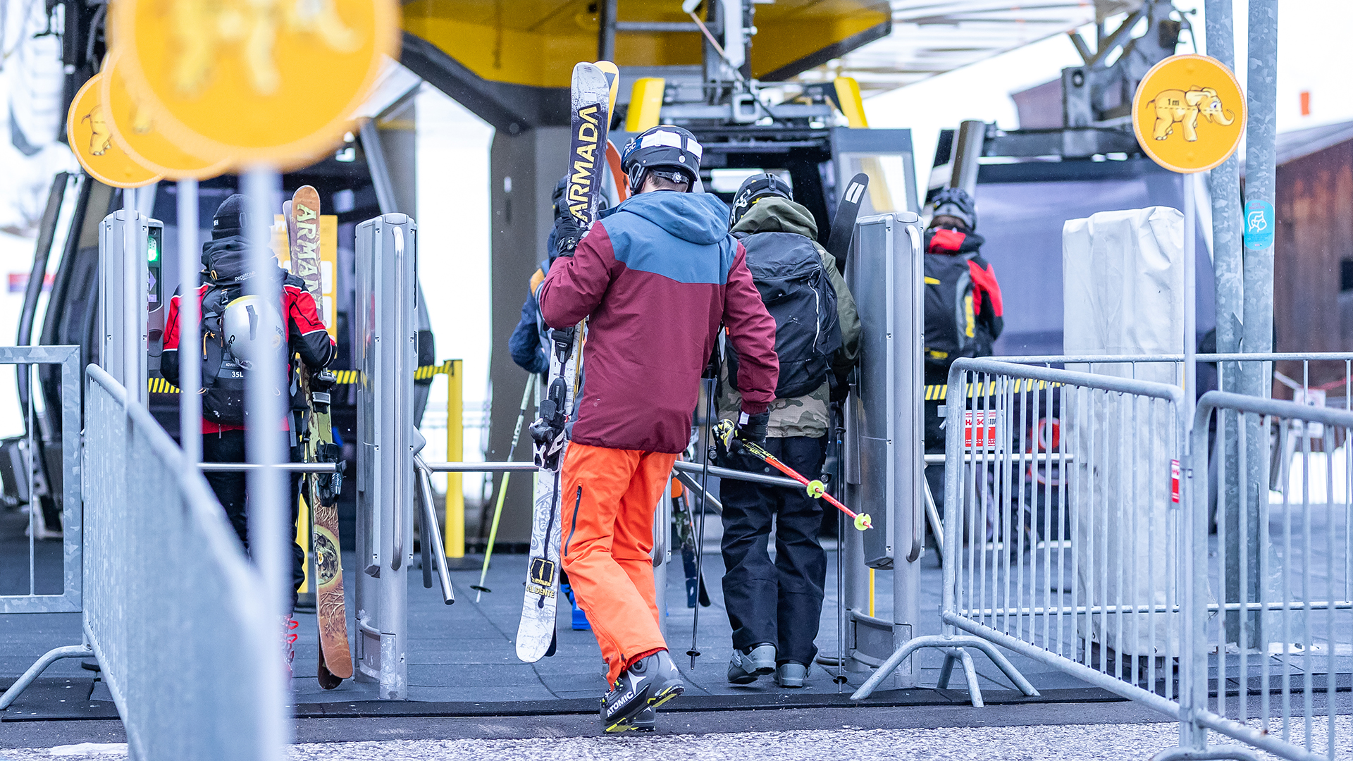 Menschen gehen mit ihren Skiern zu einer Gondel in der Talstation des Skigebiets Zillertal Arena