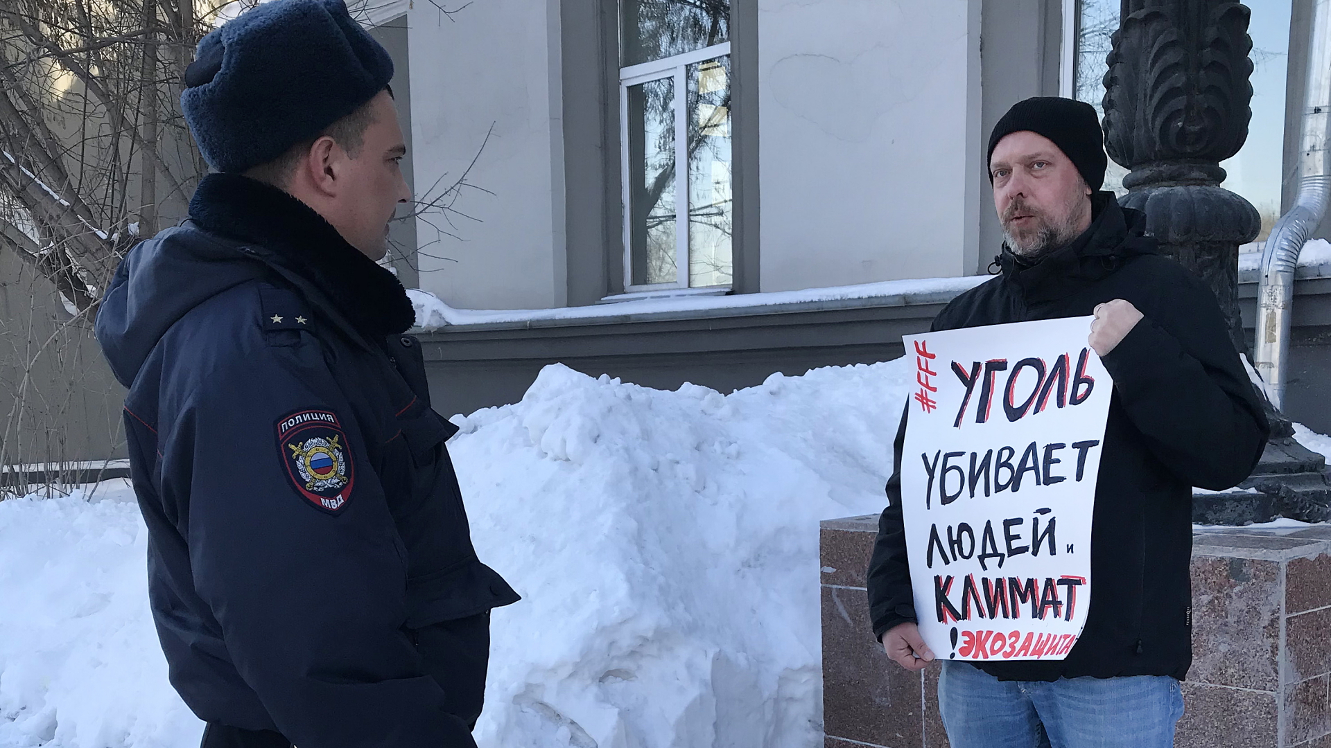  Ein russischer Milizionär studiert im März 2020 ein Protestplakat, mit dem der Umweltschützer Wladimir Sliwjak auf die Folgen der Kohle für das Klima und die Menschen hinweist | dpa
