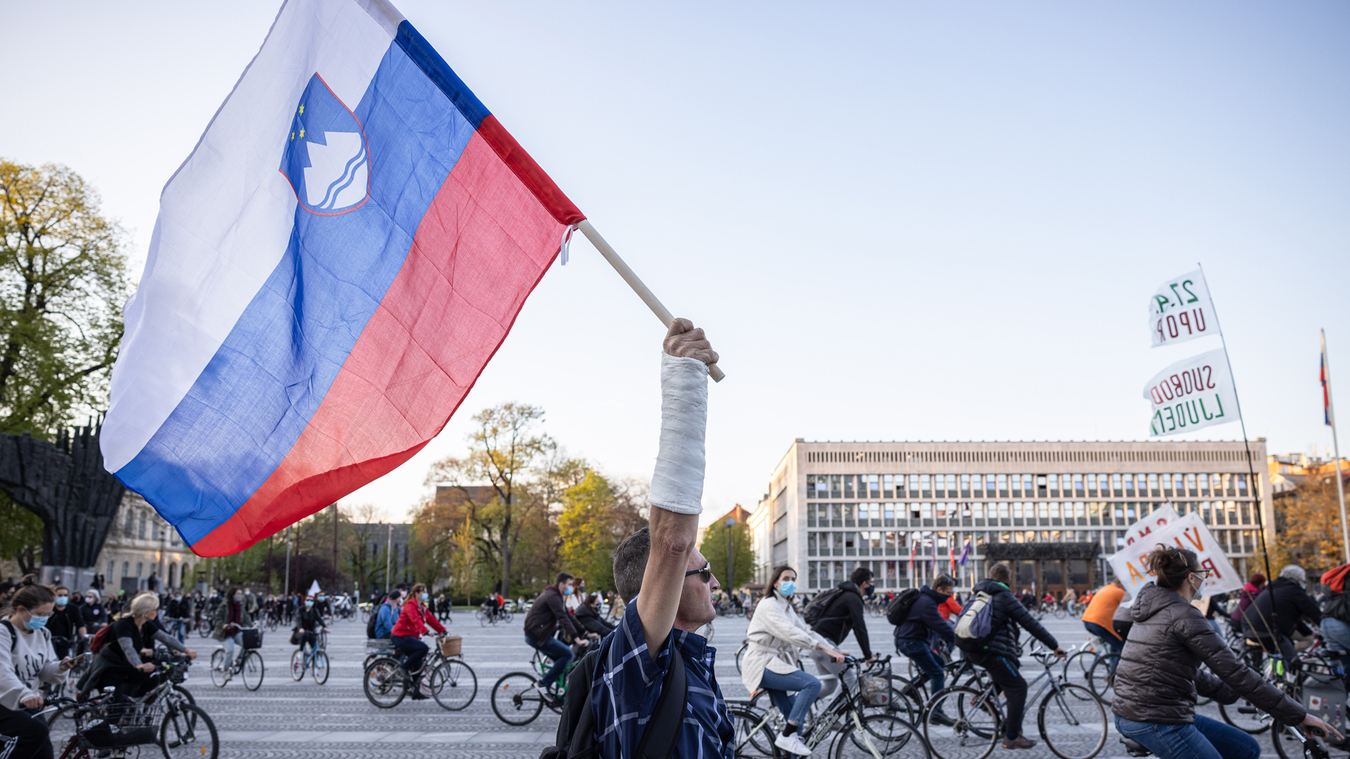Ein Mann mit Gipsarm hält auf einem Protest gegen die Regierung die slowenische Flagge hoch. | picture alliance / ZUMAPRESS.com