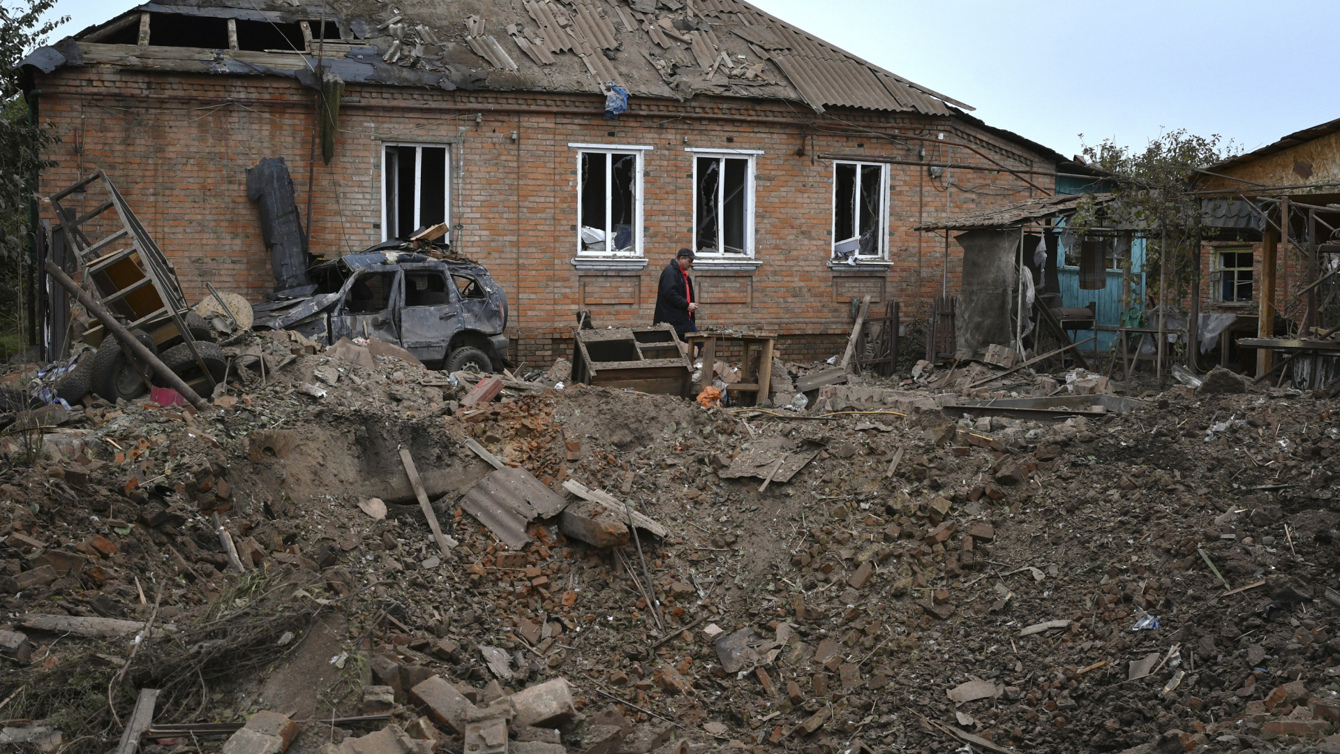 Ein Krater vor einem durch russischen Beschuss beschädigten Haus in Slowjansk. | AP