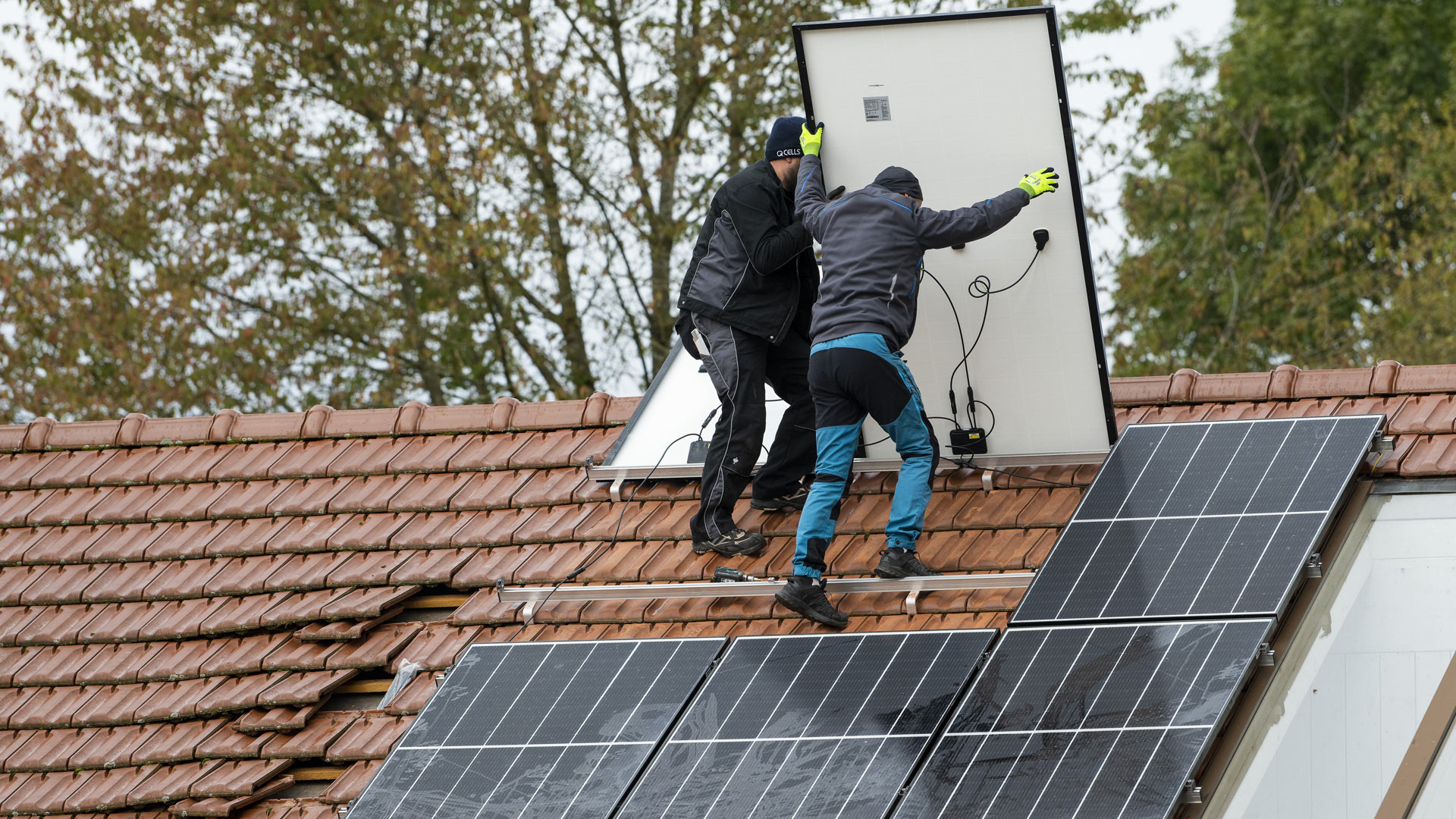 Techniker montieren eine Photovoltaikanlage auf dem Dach eines Wohnhauses 