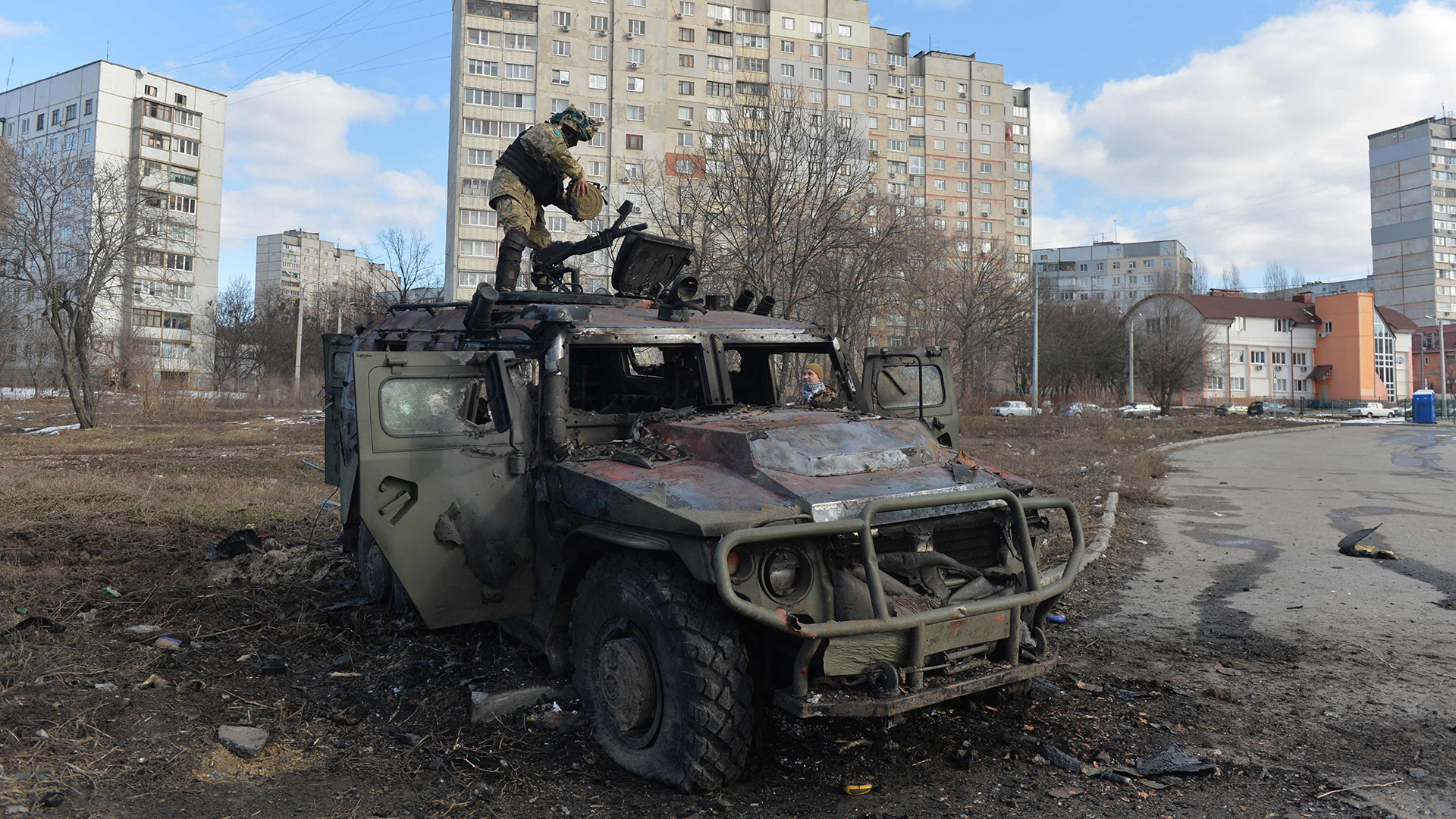 Ein ukrainischer Soldat steht auf einem zerstörten russischen Fahrzeug in Charkiw. | AFP