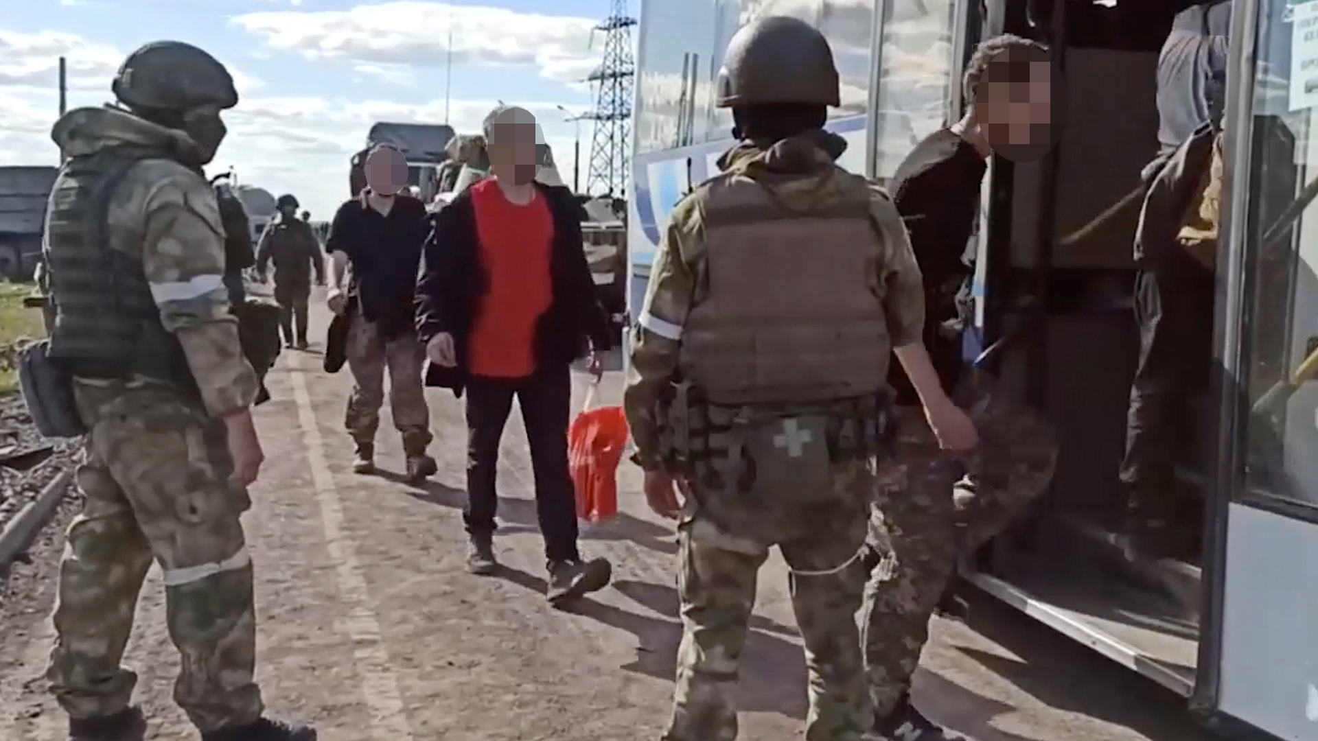 Bewacht von russischen Soldaten betreten ukrainische Soldaten einen Bus in Asowstal.