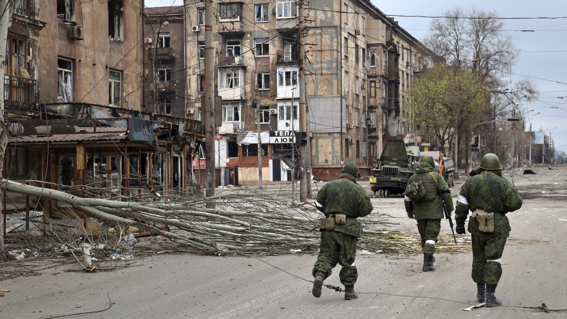 Soldaten gehen an zerstörten Wohnhäusern in Mariupol vorbei