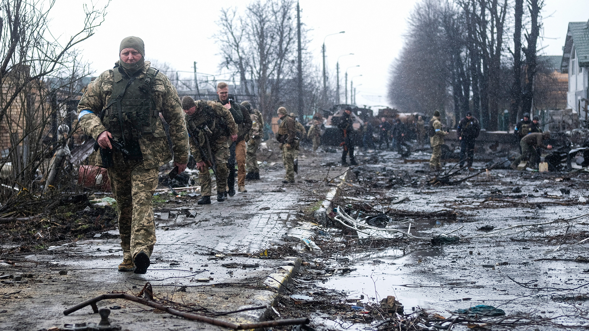 Ukrainische Soldaten inspizieren die Trümmer einer zerstörten russischen Panzerkolonne auf einer Straße in Butscha. | dpa