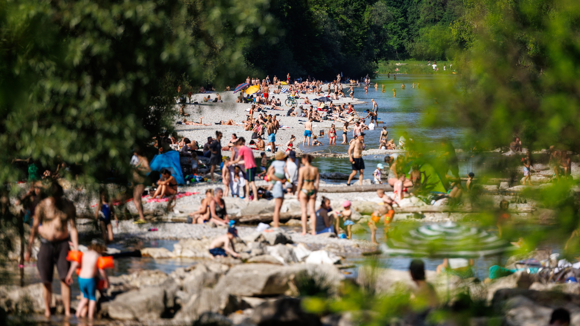 Zahlreiche Menschen baden bei sommerlichen Temperaturen am Flaucher in der Isar