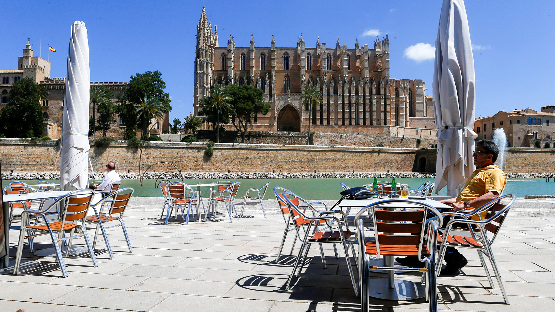  Ein Mann sitzt im Außenbereich einer Bar im Parc de la Mar. Im Hintergrund ist die Kathedrale von Palma zu sehen, Mallorca/Spanien | REUTERS