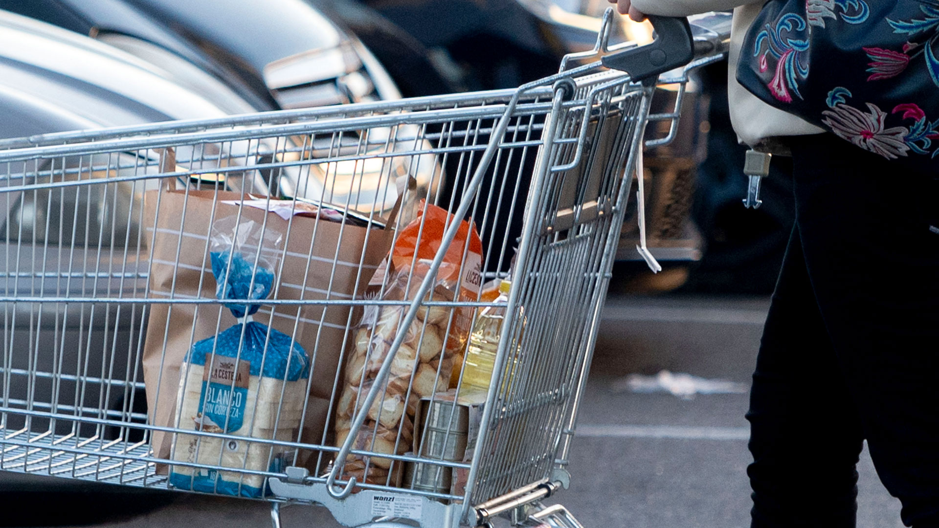 Eine Frau verlässt einen Supermarktin Spanien mit einem Einkaufswagen. | picture alliance / abaca