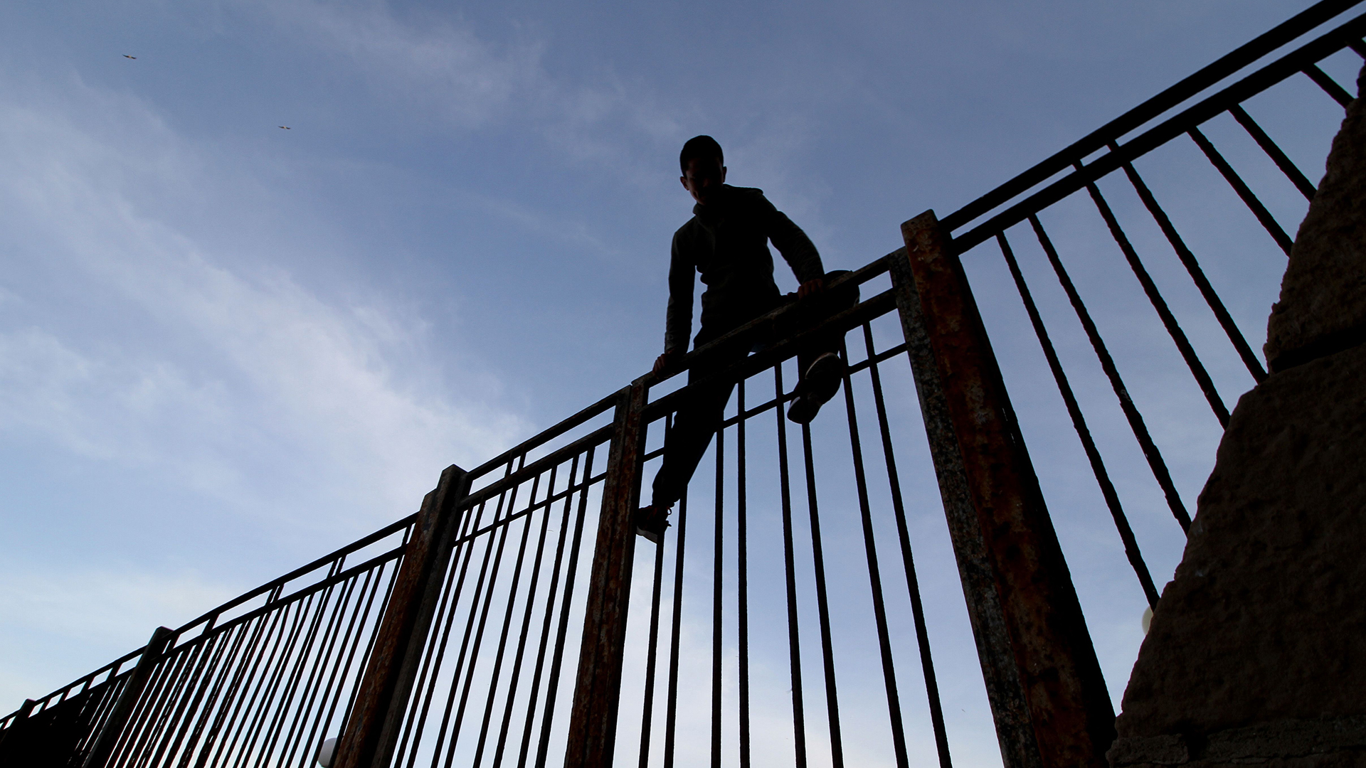 Ein Marokkaner klettert über den Grenzzaun in Melilla | AFP