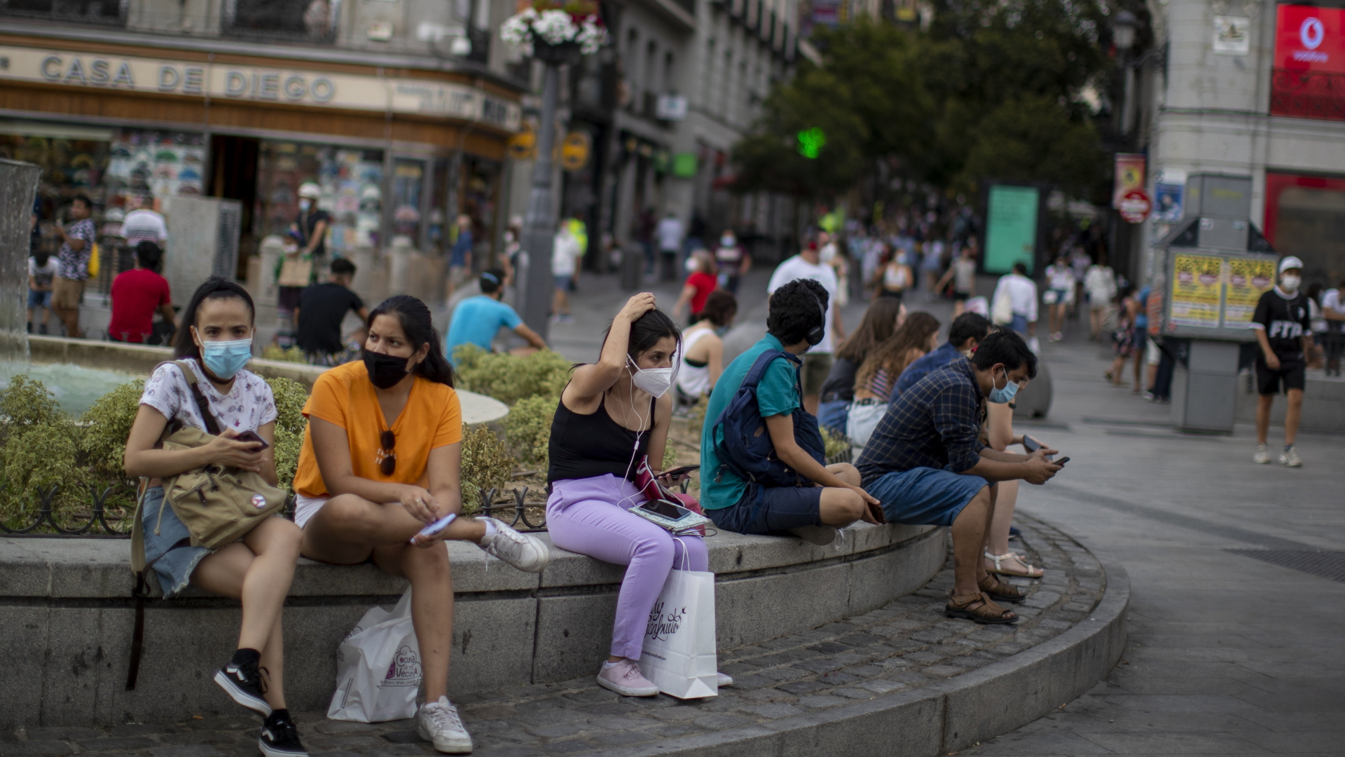 Junge Erwachsene sitzen an einem Brunnen in Madrid | AP
