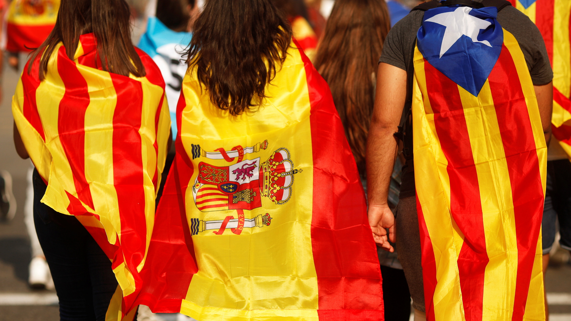 Jugendliche gehüllt in unterschiedliche Flaggen - eine spanische, eine katalonische und eine der katalonischen Unabhängigkeitsregierung