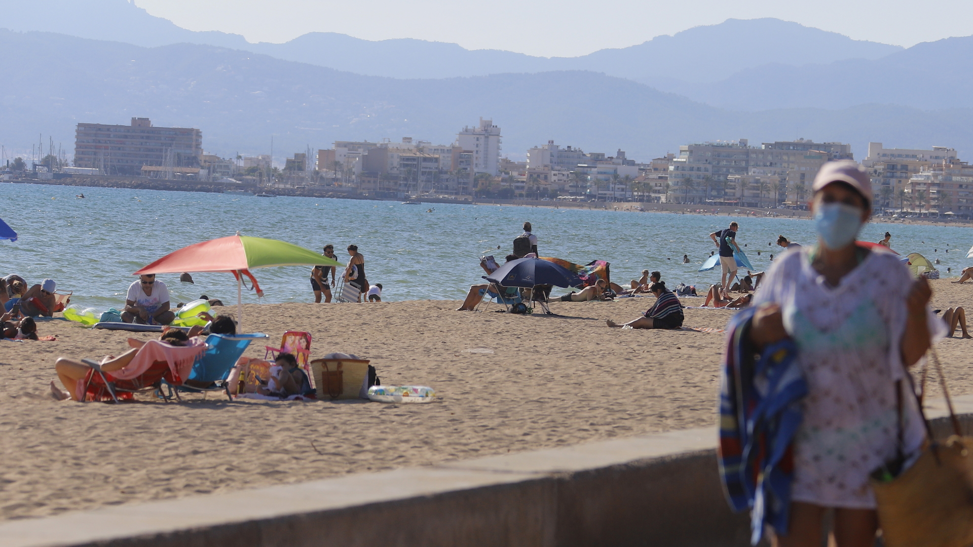 Eine Frau läuft mit maske an einem Strand in Palma de Mallorca entlang. | dpa