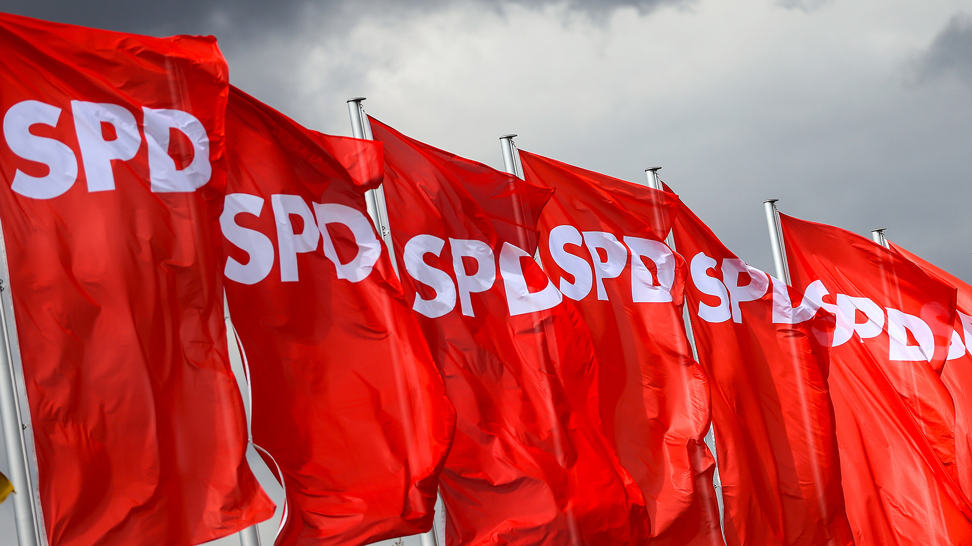 SPD-Fahnen wehen vor dunklen Wolken
