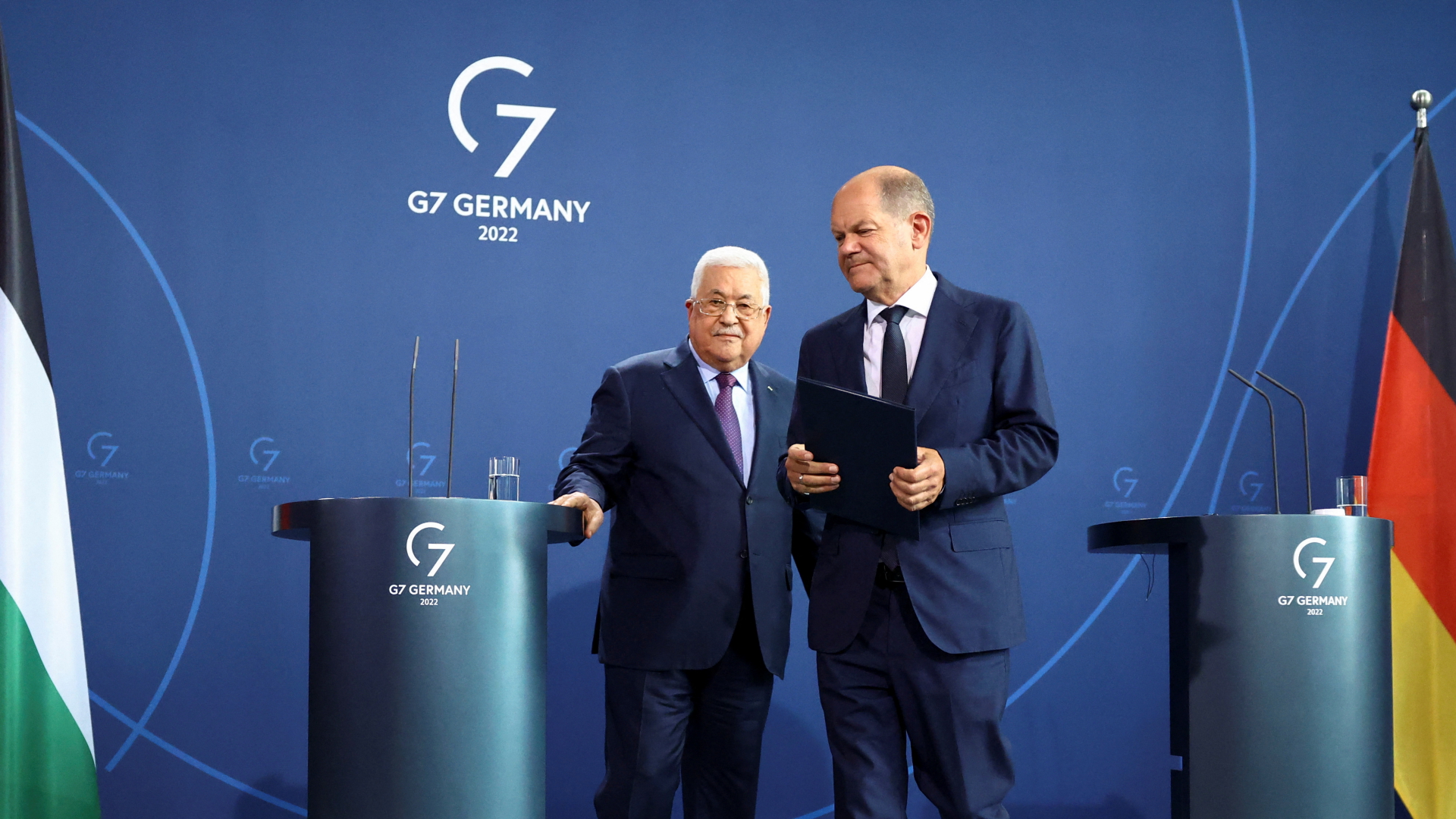 Bundeskanzler Olaf Scholz richtet bei einer Pressekonferenz mit Palästinenserpräsident Abbas Mitte August 2022 sein Mikrofon im Ohr. | REUTERS
