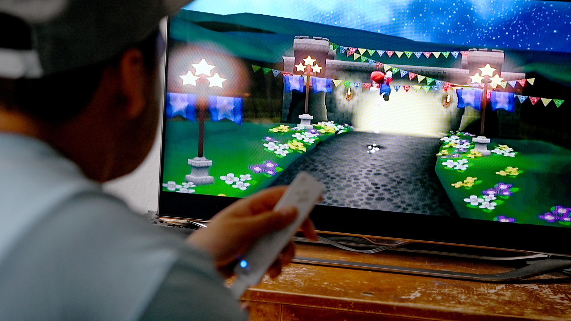 Ein junger Mann spielt mit der Spielekonsole Nintendo Wii vor dem Fernseher.