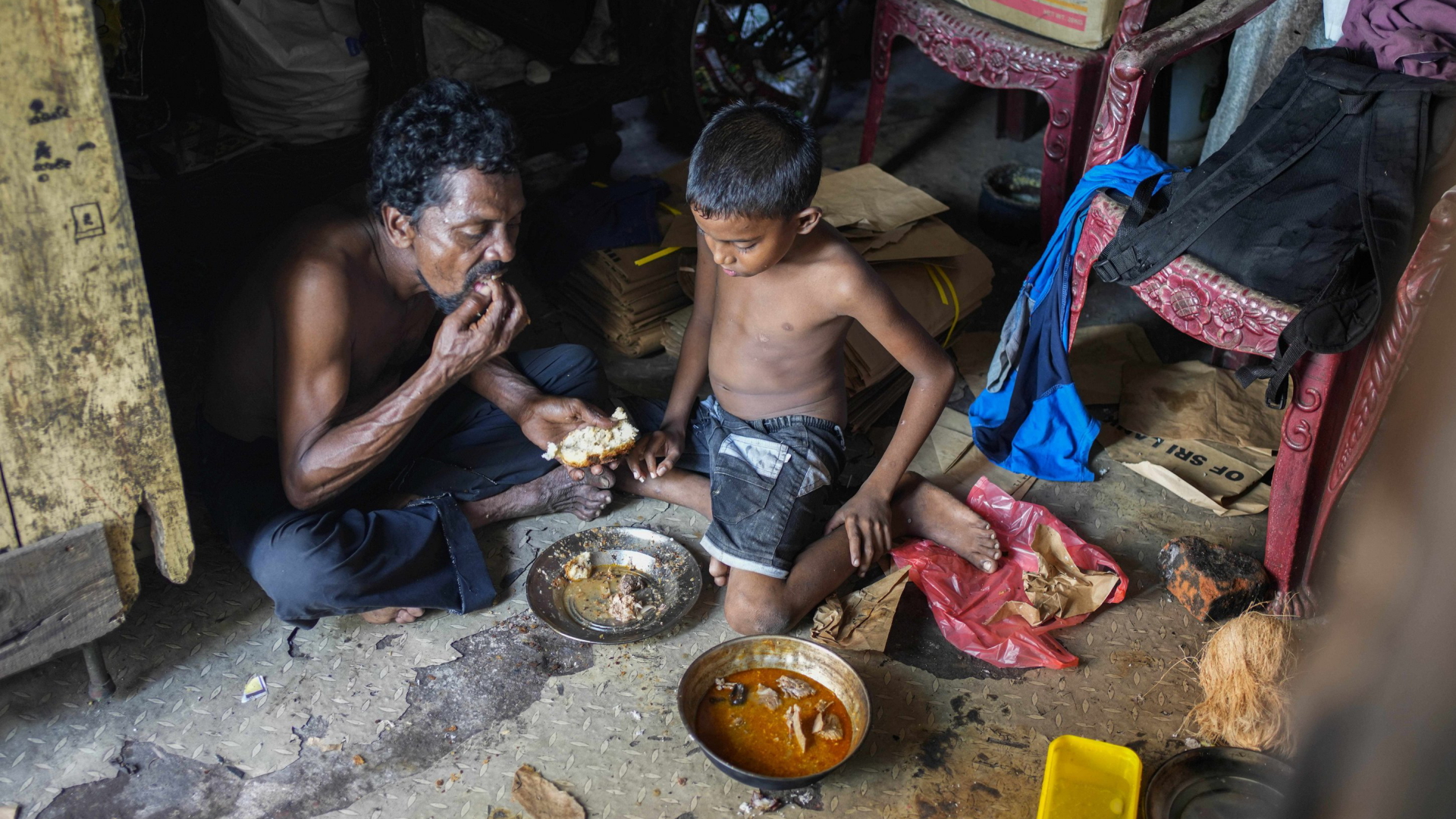 Ein Vater und sein Sohn nehmen in ihrer Behausung in Colombo (Sri Lanka) eine Mahlzeit ein