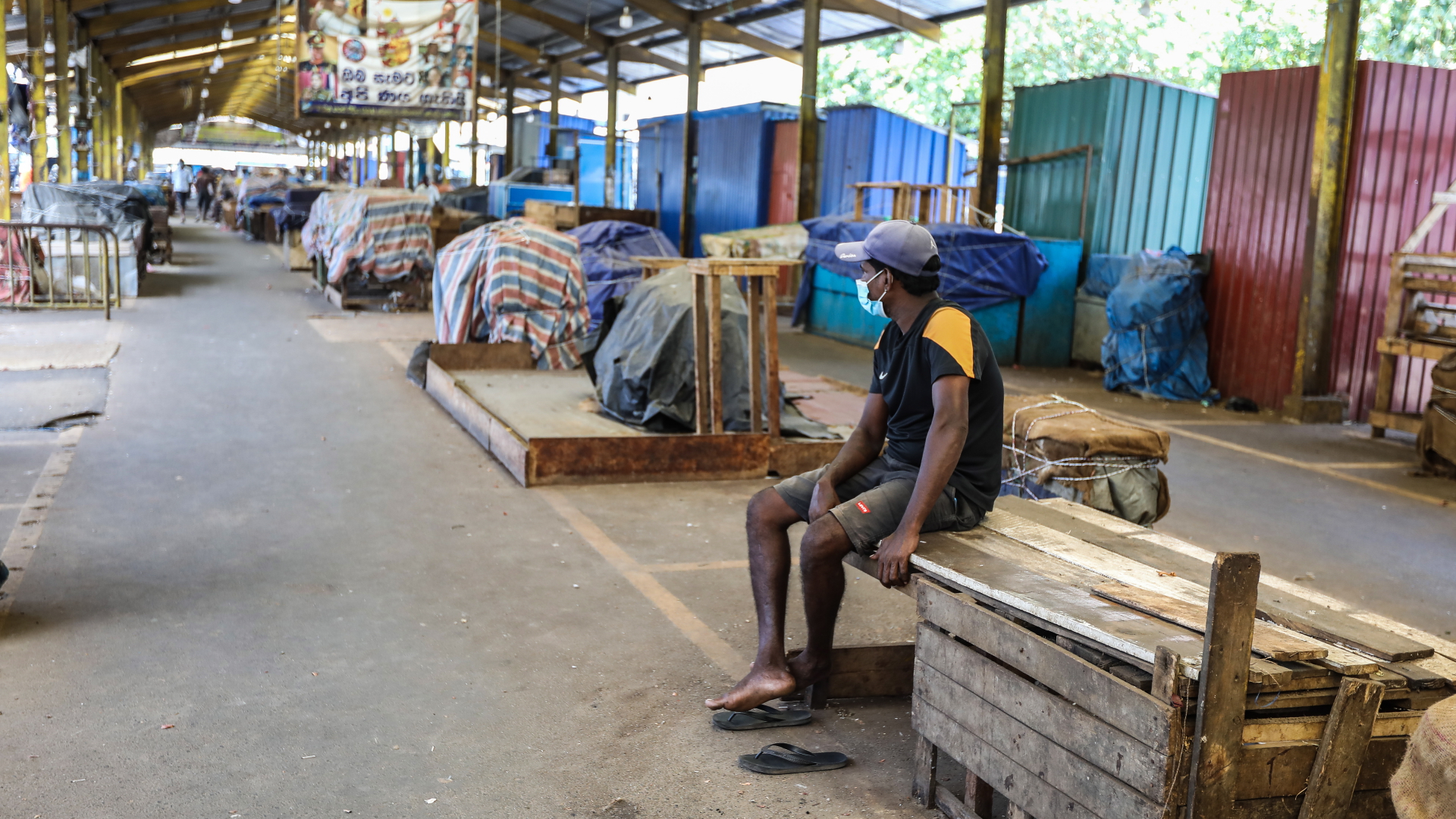 Ein Mann sitzt in einer leerne Markthalle, die wegen eines Corona-Lockdowns in Sri Lankas Hauptstadt Colombo geschlossen hat (Foto vom 10.09.2021). | EPA