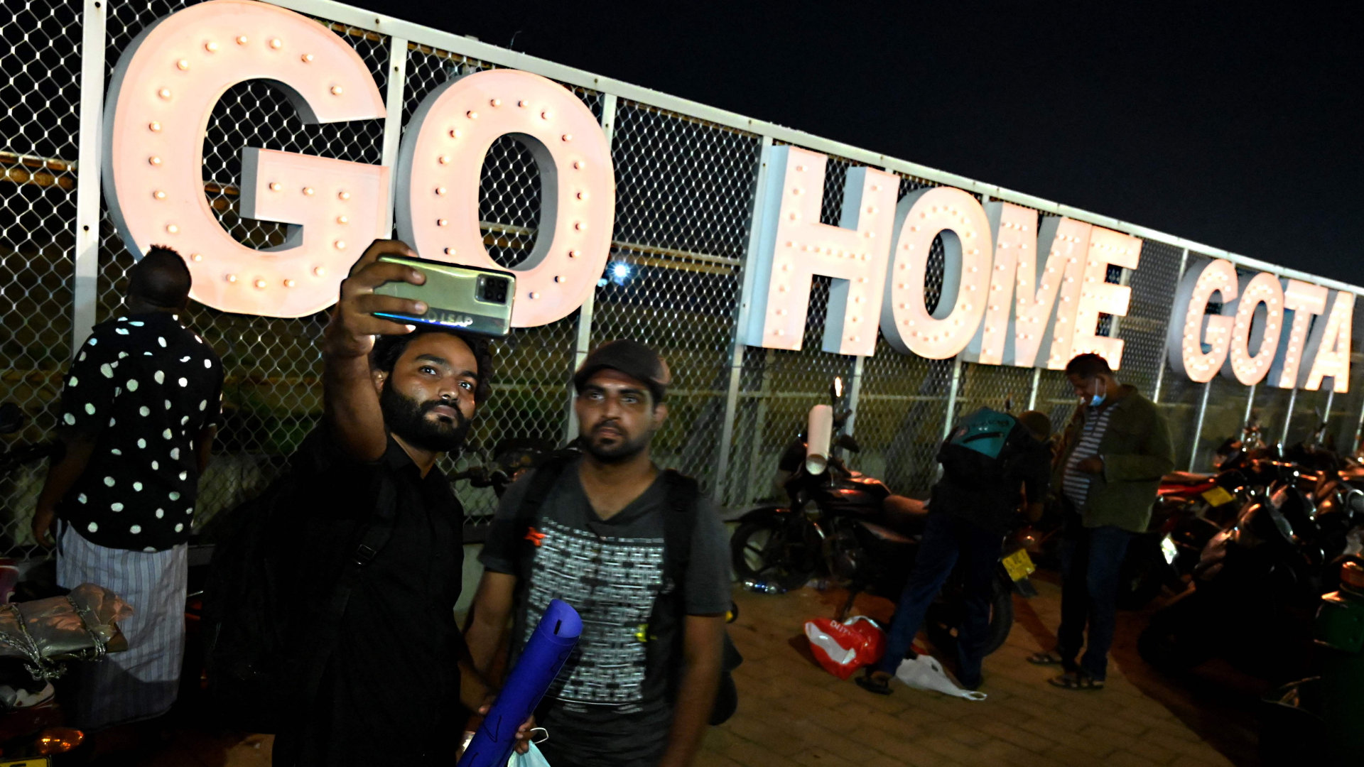Demonstranten in Colombo (Sri Lanka) fotografieren sich vor einem Schriftzug "Go home Gota" | AFP