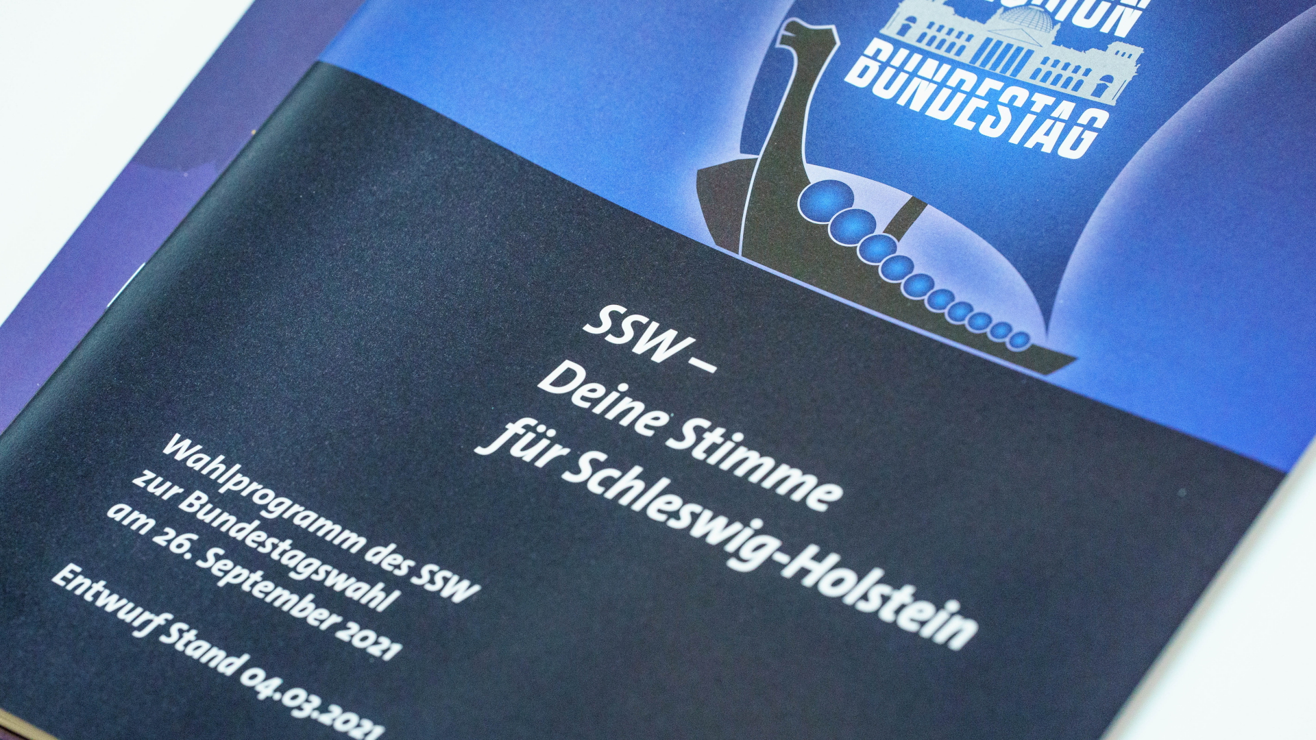 Das Wahlprogramm des Südschleswigschen Wählerverbands (SSW) liegt während eines außerordentlichen Landesparteitags zur Spitzenkandidatur für die Bundestagswahl in der A. P. Moeller-Schule auf einem Tisch.  | dpa